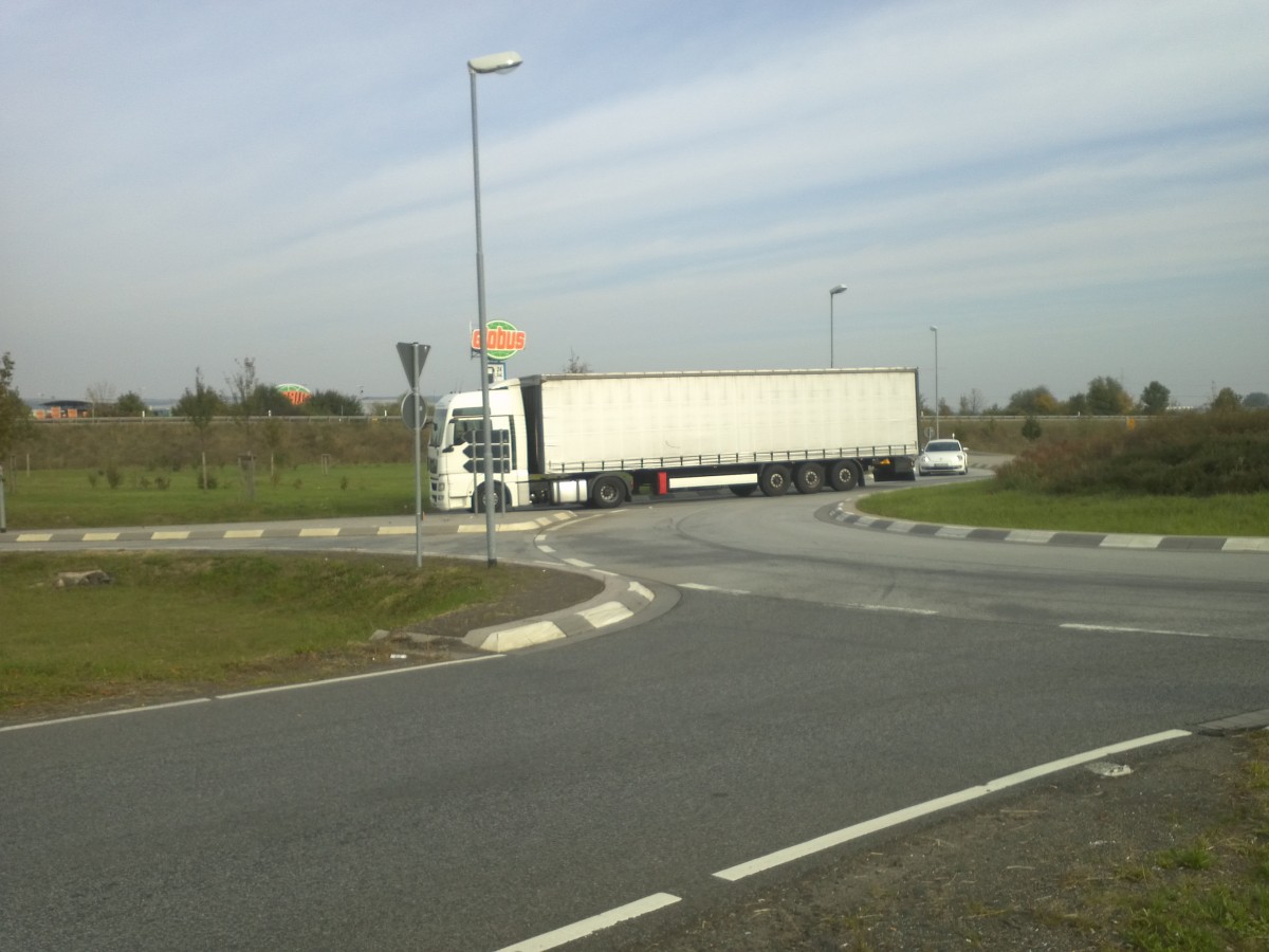 LKW SZM MAN TGA mit Pritsche-Planen-Auflieger beim Verlassen des Autohofes in Grnstadt am 01.10.2013