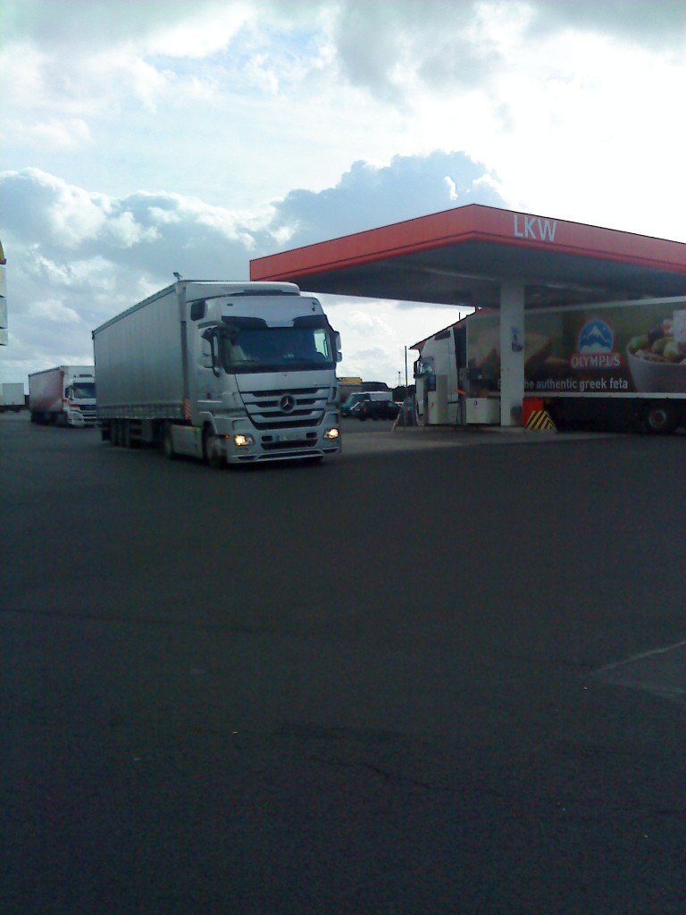 LKW SZM Mercedes-Benz Actros 1844 mit Pritsche-Planen-Auflieger beim Verlassen des Autohofes in Grnstadt am 30.10.2013