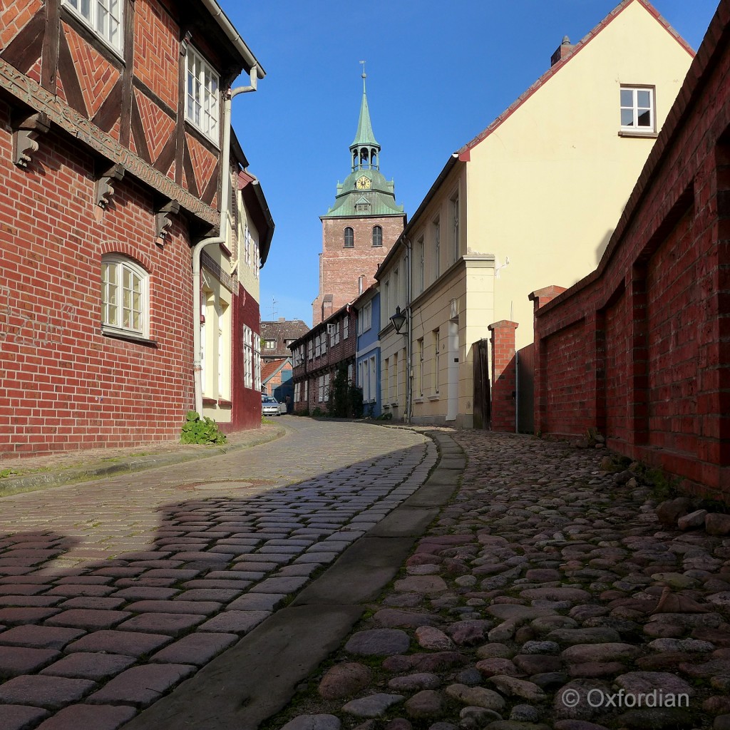 Lüneburg - Gasse mit Kopfsteinpflaster. Im Bildhintergrund die Kirche St. Michaelis.