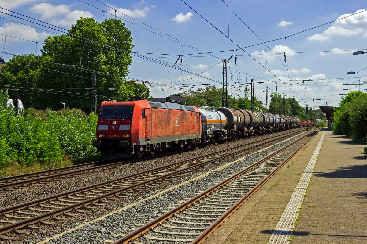 Mit einem gemischten Gterzug, der unter anderem aus einer Wagengruppe Kesselwagen besteht, ist 185 049 am 30.07.22 in Hilden unterwegs.