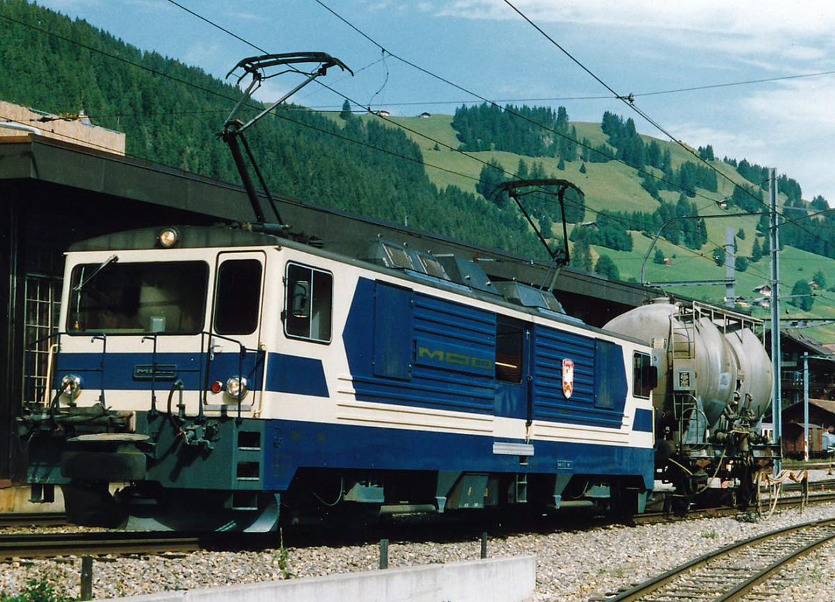 MOB: Während den vielen Jahren, da ich die MOB fotografierte, erlebte ich nie einen eihheitlichen Farbanstrich. Bereits die im Jahre 1983 in den Betrieb gestellten GDe 4/4 6001 bis G004 wurden in einem eher dunkelblauen Farbkleid abgeliefert. Bald aber ist die ursprüngliche einheitliche Farbgebung durch die verschiedesten Werbeaufschriften verdrängt worden. GDe 4/4 6002 im Ablieferungszustand mit einem Rollbockzug in Zweisimmen im Jahre 1984.
Foto: Walter Ruetsch    