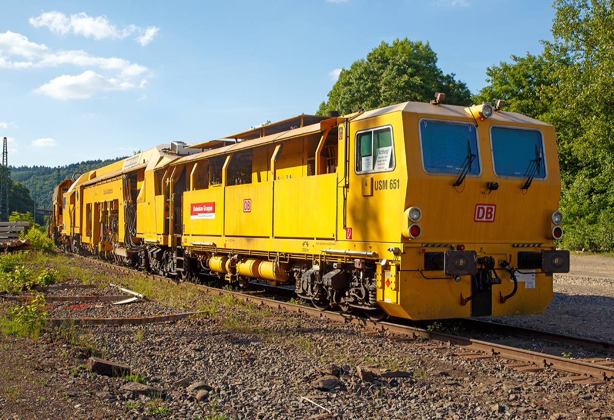 
Plasser & Theurer Universalstopfmaschine UNIMAT 09 - 16 / 4S (Schweres Nebenfahrzeug Nr. 97 43 51 001 17-3)  USM 651  „Yellow Submarine“  der DB Bahnbau Gruppe, abgestellt am 14.06.2017 in Betzdorf/Sieg abgestellt. Ehemals gehörte die Maschine der DB Netz AG, Maschinenpool (Netz Instandhaltung).

Die Universalstopfmaschine mit der internen DB Bezeichnung USM 651 wurde 2002 von Plasser & Theurer in Linz (A) unter der Fabriknummer 3023 gebaut.

Die Universalstopfmaschine Unimat 09-16/4S für Gleise und Weichen verfügt über vier unabhängig voneinander arbeitende Stopfaggregate mit insgesamt 16 Stopfpickeln. Bei der Gleisdurcharbeitung ist kontinuierliches Fahren und zyklisches Stopfen bis weit in den Weichenbereich hinein möglich

Funktionsmerkmale der USM Unimat 09-16/4S: 
- die vier Stopfaggregate können gedreht, einzeln seitlich verschoben und somit vor jedem Stopfgang optimal positioniert werden
- für das Stopfen von Langschwellen werden die außen liegenden Stopfaggregate mit horizontalen Teleskop-Führungssäulen seitlich ausgefahren (Vierstrang-Stopfung)
- kontinuierliches Fahren und zyklisches Stopfen bis weit in den Weichenbereich hinein
- Durcharbeitung von Weichen erfolgt mit Dreistrang-Hebung und Vierstrang-Stopfung
- eine automatisch arbeitende Zusatzeinrichtung gewährleistet die Hebung des dritten Stranges
- Richtungslaser zum Verlängern der Messbasis in der Geraden
- 6-Kanal-Schreiberanlage zur Dokumentation der Gleißlage und Arbeitsqualität 
- Vibrationsverdichter
- automatischer Leitcomputer ALC mit EM-SAT Datenverarbeitung
- automatische Toleranz-Überwachung für Arbeitsqualität der Maschine
- Korrektursteuerung für Höhe, Längshöhe, Richtung, Überhöhung

TECHNISCHE DATEN:
EBA-Nummer: EBA 00 A 11 003
Spurweite: 1.435 mm (Normalspur)
Anzahl der Achsen: 8 davon 4 angetrieben
Achsfolge: 2' 2'+Bo' Bo' 
Länge über Puffer:  33.140 mm
Drehzapfenabstände: 10.000 mm / 3.500 mm / 14.000 mm
Achsabstand im Drehgestell: 1.800 mm
Raddurchmesser (neu): 920 mm
Eigengewicht: 131.000 kg
Nutzlast: - t
Zul. Anhängelast: 60 t
Leistung: ca. 500 kW 
Zur Mitfahrt zugel. Personenzahl: 6
Kleister befahrbarer Gleisbogen: R = 120 m (Arbeitsradius  min.  150 m)
Zugelassen für Streckenklasse: C2 und höher
Höchstgeschwindigkeit: 100 km
Bremse: KE-GP mZ K
Bremsgewichte: G 102 t / P 108 t

Arbeitsleistung bei Durcharbeitung im Gleis:  600 m/h
Arbeitsleistung bei Durcharbeitung von Weichen : 1 /h