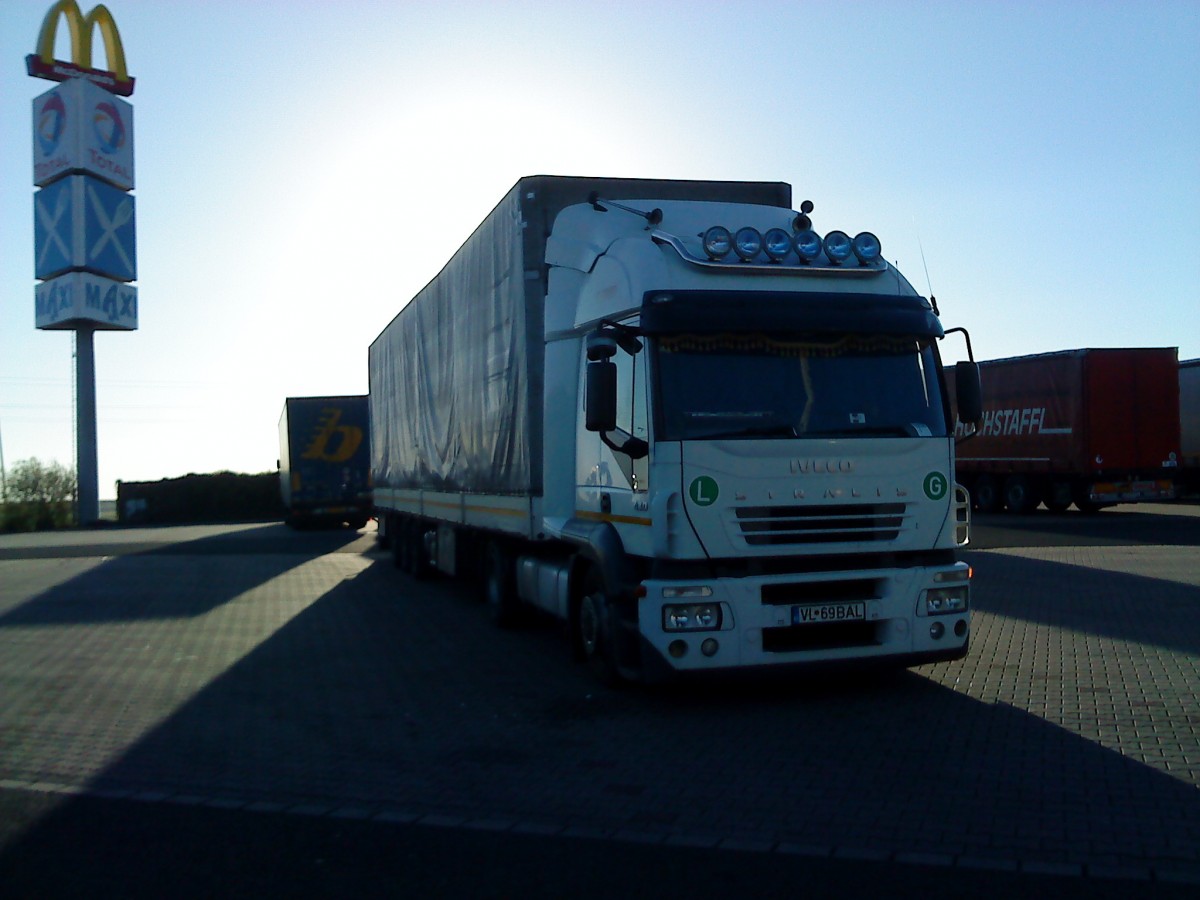 SZM IVECO Stralis mit Pritsche-Planen-Auflieger auf dem Autohof in Grnstadt am 25.11.2013