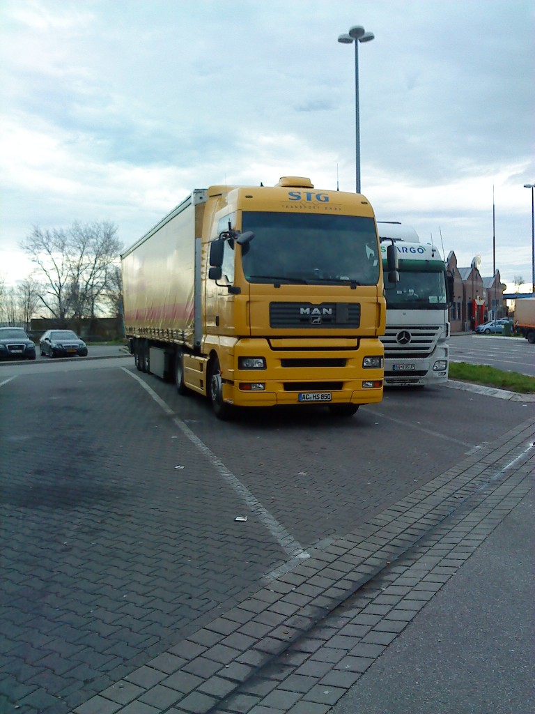 SZM MAN TGX 18.440 mit Pritsche-Planen-Auflieger der DHL auf dem Parkplatz an der Raststtte Schifferstadt am 06.01.2014