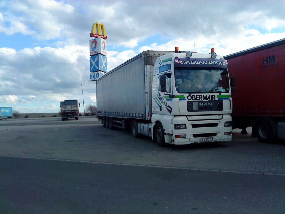 SZM MAN TGX 18.440 mit Pritsche-Planen-Auflieger der Spedition Obermair Spezialtransporte gesehen auf dem Autohof in Grnstadt am 18.02.2014