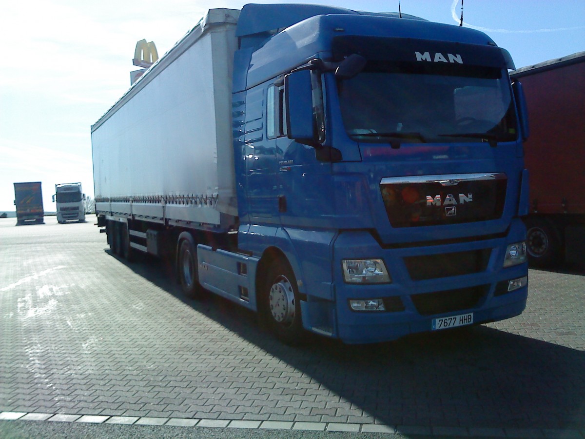 SZM MAN TGX 18.440 mit Pritsche-Planen-Auflieger gesehen auf dem Autohof in Grnstadt am 20.03.2014