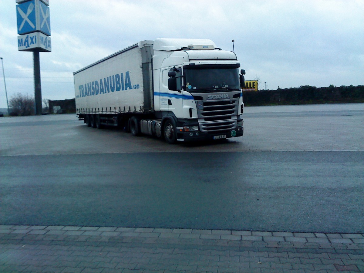 SZM SCANIA R 420 mit Pritsche-Planen-Auflieger der Spedition Transnubia auf dem Autohof in Grnstadt am 19.12.2013





