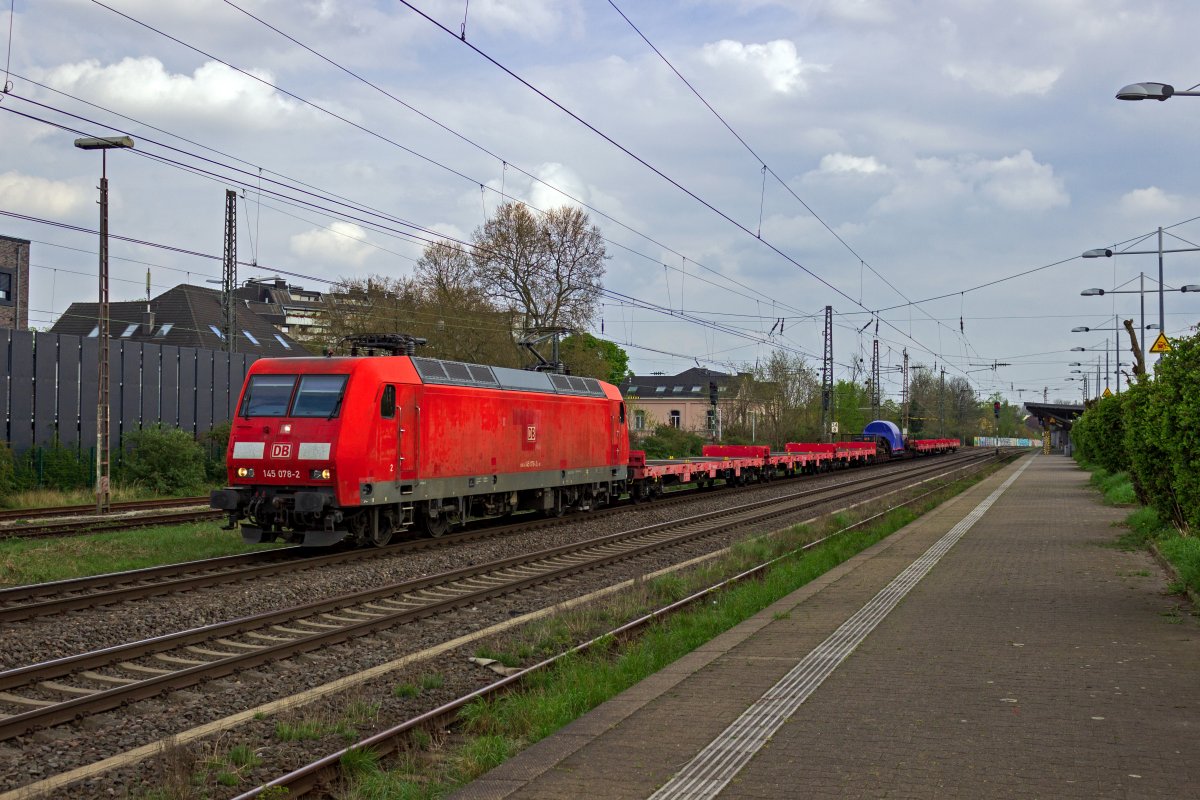 Tiefladewagen fr Schwerlasttransporte gehren zu den selten anzutreffenden Fahrzeugen auf deutschen Schienen. 145 078 schleppt einen Wagen der Bauart Uaais 819 mit einem nicht zu identifizierenden, aber sicherlich schweren Ladegut durch Hilden. Um die Bremskraft des Zuges zu verbessern sind neben dem zwlfachsigen Tiefladewagen sechs weitere leere Flachwagen in den Zug eingereiht.