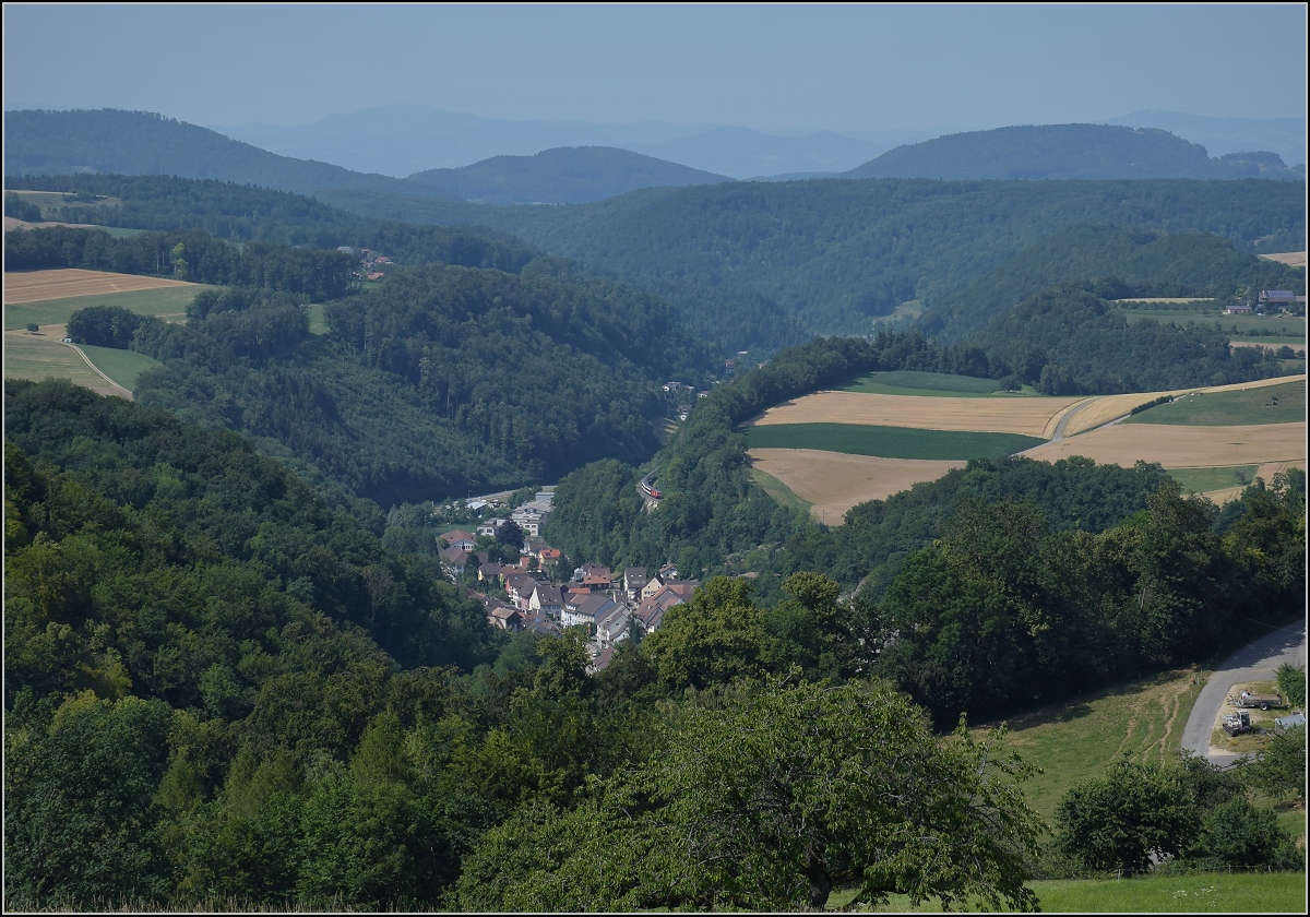 Umleiterverkehr auf dem Läufelfingerli. Die alte Hauensteinberglinie ist während der Gleisbauarbeiten bei Tecknau die Ausweichstrecke für nordwärts fahrende Züge. Hier sieht man schön die Hügel des Jura, im Hintergrund schon den Schwarzwald mit dem markanten Blauen. Erst bei genauem Hinsehen sieht man hier den Zug in der Bildmitte bei Bukten. Juli 2018. 

Der verantwortliche leitende Ingenieur Carl von Etzel war zuvor für den Bau der Geislinger Steige verantwortlich, später auch für die Brennerstrecke. Aber nicht nur der Erbauer, auch die Geologie und der frühe Bau als Bergstrecke lässt diese Linie als Schweizer Schwester der Geislinger Steige erscheinen.