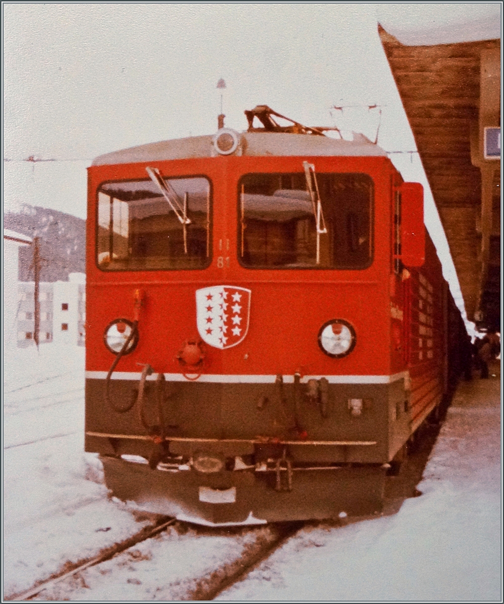 Vor dem Einsatz als  Tunnellok  für die Autozüge durch den Furkatunnel hatte die FO keinen Bedarf an den bereits erhaltenen zwei Ge 4/4 III 81 und 82 und so wurden sie bei der RhB eingesetzt. Im Bild die FO Ge 4/4 III 81  Wallis  abfahrbereit mit einem Reisezug nach Landquart in Davos Platz. Analog Bild vom Winter 1981/82 