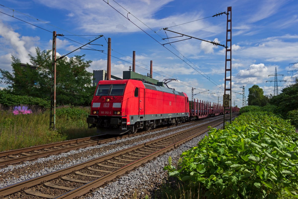 Vor der Kulisse der Kokerei Prosper in Bottrop fhrt 185 352 am 18.08.2020 an der Spitze eines mit Stahlbarren beladenen Gterzuges entlang.