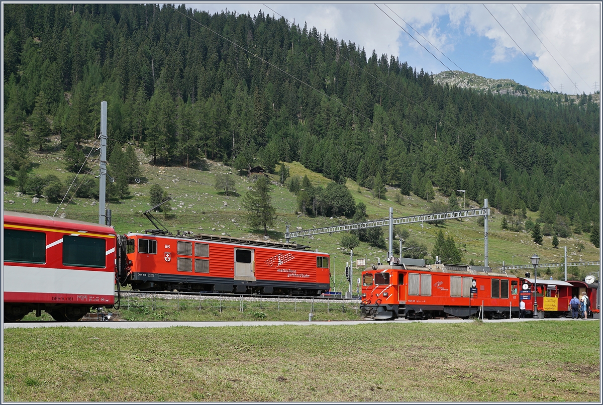 Während die MGB Gm 4/4 61 im DFB Bahnhof von Oberwald rangiert, fährt im MGB Bahnhof ein Regionalzug Richtung Andermatt aus..

31. August 2019