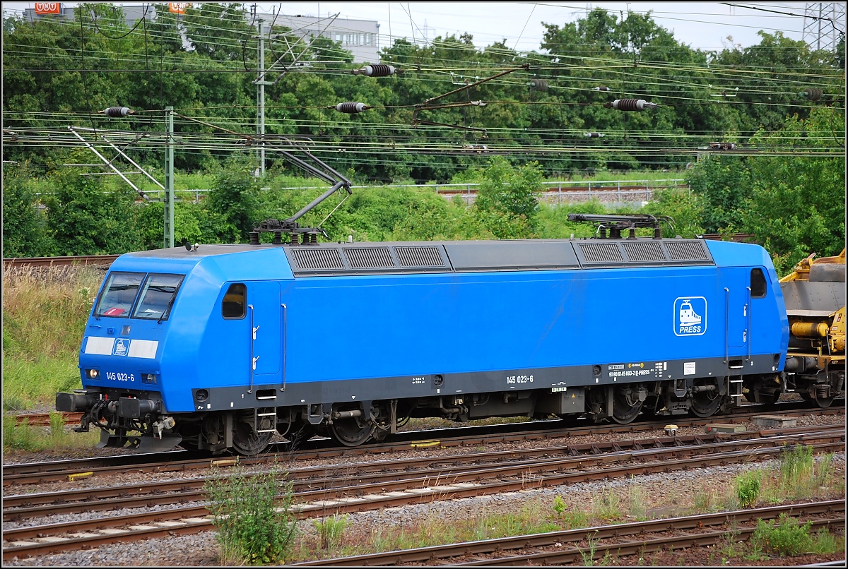 Wer genau hinschaut, erkennt ansatzweise die Aufschrift Re 481 001-6 aus ihrer SBB-Zeit. Sie war im Jahr 2000 als Re 486 651-3 an die MThB ausgeliefert worden. Kurz vor der Zerschlagung der MThB wurde sie an die SBB verkauft. 2005 kam sie zur MRCE und 2006 schließlich zur Press. Dort erhielt sie die NVR-Nummer 9180 6 145 083-2 und die blaue Haut. Die eigenwillige interne Bezeichnung der Press ist 145 023-6. Wie sie aber zur falschen Kontrollziffer 6 gekommen ist, bleibt wohl des Besitzers Geheimnis. Sie ist nicht zu verwechseln mit der 145 023-8 der DB. Das Bild entstand im Juni 2009 in Wiesbaden, wo sie einen Bauzug zur Baustelle auf der rechten Rheintalbahn brachte. 
