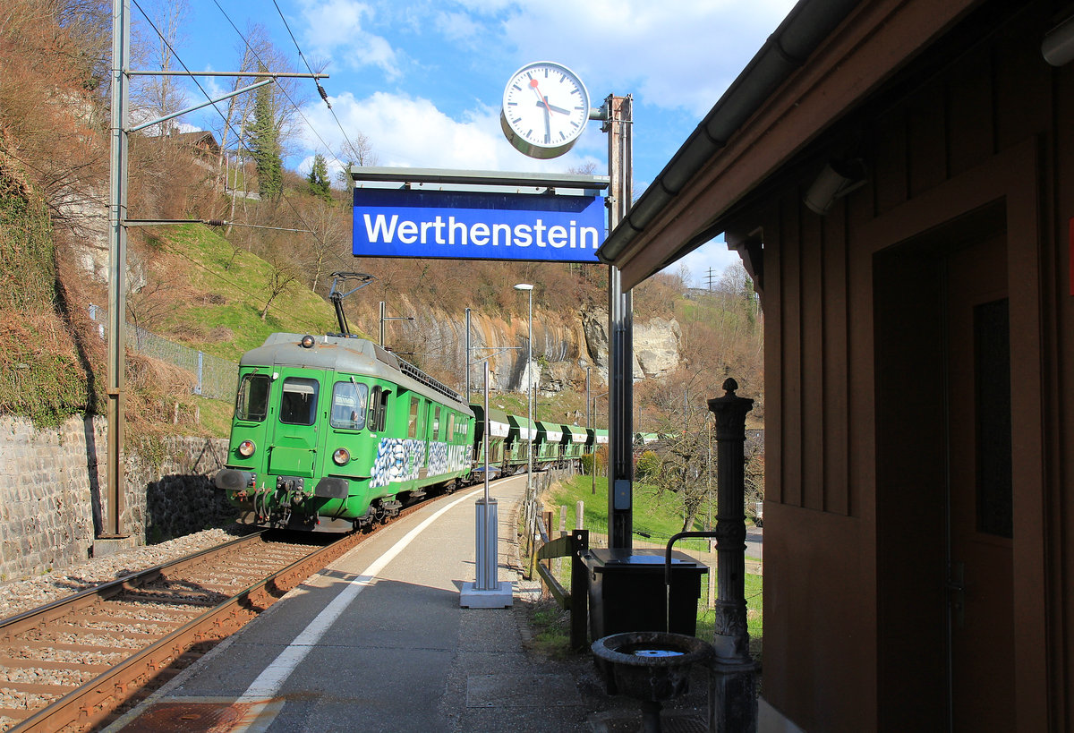 Werthenstein: Durchfahrt eines Kieszuges mit Makies-Triebwagen 576 049  Babette , ehemals SOB Triebwagen BDe 4/4 81 von 1959. Der kleine alte Brunnen am Bahnhof wirkt dabei ganz vertrumt. 25.Mrz 2021  