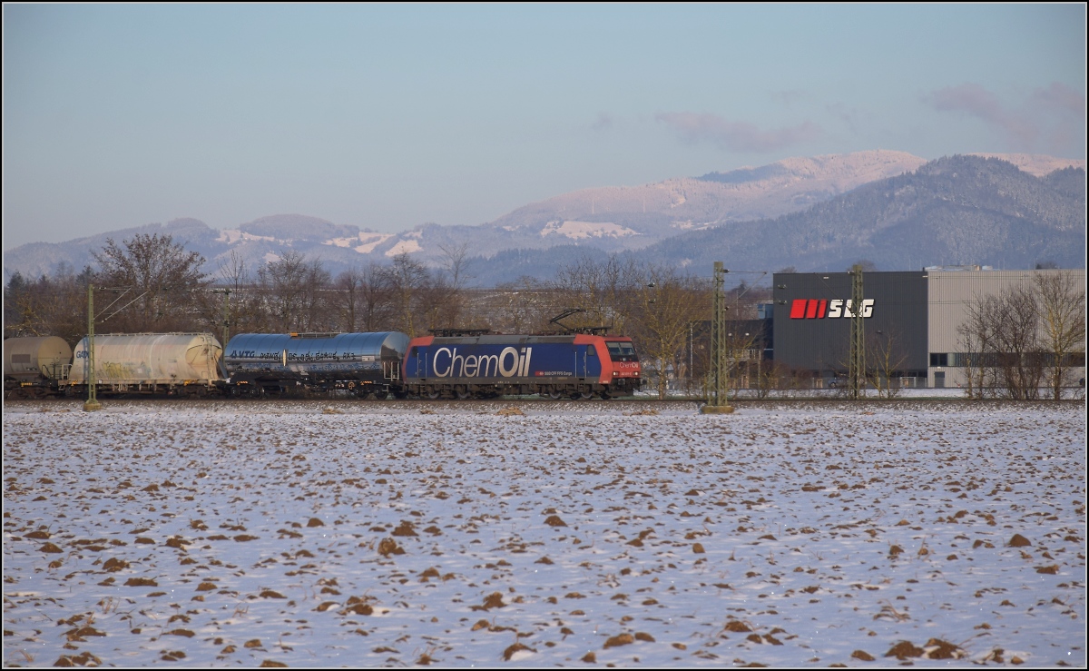 Zwischen Belchensystem und Blauendreieck. 

SBB Cargo Re 482 015 mit ChemOil-Werbung Richtung Basel bei Buggingen, während sich im Hintergrund der Schauinsland aus den Wolken geschält hat. Februar 2021.