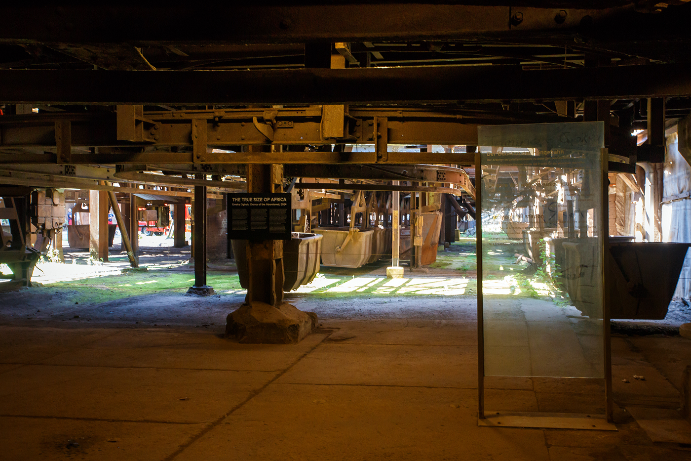 Auch eine Eisenbahn (Schwebebahn): Die H�ngebahn der V�lklinger H�tte am 01 Juli 2025, hier einer der selbstfahrenden H�ngebahnwagen unter der M�llerhalle. 

Die H�ngebahn ist eine Einschienenbahn bzw. Schwebebahn mit selbstfahrende H�ngebahnwagen, bei den Schr�gaufz�gen auf die Gichtb�hne wurden sie mit Seilz�gen unterst�tzt. 

Die H�ngebahn war seit 1911 in Betrieb. 1985 fuhren pro Stunde 240 beladene H�ngebahnwagen zur  Gicht . Sie liefen �ber die sogenannte Gichtb�hne in einer H�he von 27 Metern, die Rohstoffe (Eisenerz, Sinter, Schrott, Kalk und Koks) um die 6 Hoch�fen von dort zu beschicken. Die Gleisl�nge der H�ngebahn betrug �ber 6 km.

Der M�ller (Eisenerz, Sinter, Schrott und Kalk wurden in der M�llerhalle (s�d�stlich der Hoch�fen) in selbstfahrende H�ngebahnwagen verladen und �ber einen vierspurigen Schr�gaufzug auf die Gichtb�hne gezogen. Auf der Gichtb�hne laufen mehrere H�ngebahnspuren an den sechs Hoch�fen vorbei und wieder zur�ck zum Schr�gaufzug, mit kreisf�rmigen Abzweigschleifen um jeden Hochofen herum. Auf der Nordwestseite der Gichtb�hne l�uft ein kleinerer zweispuriger Schr�gaufzug hinunter zur Kokerei, um den Koks f�r die Hoch�fen zu f�rdern.

Die Gichtb�hne verbindet alle sechs Hoch�fen mit einer Ebene. Auf dieser Ebene werden die H�ngebahnwagen entlanggef�hrt. Die Gichtb�hne ist ca. 240 Meter lang und erstreckt sich in einer H�he von exakt 27 Meter.  Die Gichtb�hne hat Ihren Namen von dem Wort  Begichten , was das Bef�llen der Hoch�fen mit den Rohstoffen f�r die Eisenerzeugung bezeichnet. Eisenerz, Sinter, Zusatzstoffe, Koks, aber auch eisenhaltige Reststoffe aus der Industrie oder Schrott wurden in die Gicht, den Einf�lltrichter des Hochofens, gekippt. Die „Haube/obere Glocke“, der obere Verschluss des Hochofens, wurde angehoben, dann f�nf H�ngebahnwagen um den Trichter gefahren. Unterhalb der Haube befindet sich ein zweiter Verschluss, die „Gicht-Glocke“. Sie blieb geschlossen, um das Gichtgas aufzufangen. Das Material wurde auf die Glocke gekippt, dann die Haube abgesenkt. Erst wenn die Haube geschlossen war, wurde die Glocke nach unten gefahren: Das Material rutschte in den Hochofenschacht. Diese Verschlussart nannte man „Doppelglockenverschluss“, bei modernen Hoch�fen werden heute glockenlose Gichtverschl�sse verwendet. 
