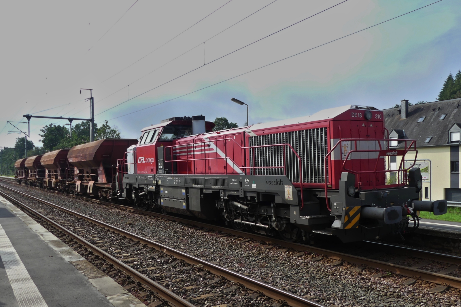 CFL DE 18 310, steht mit einigen mit Schotter gefüllten Güterwagen im Bahnhof von Wilwerwiltz. 25.08.2023  