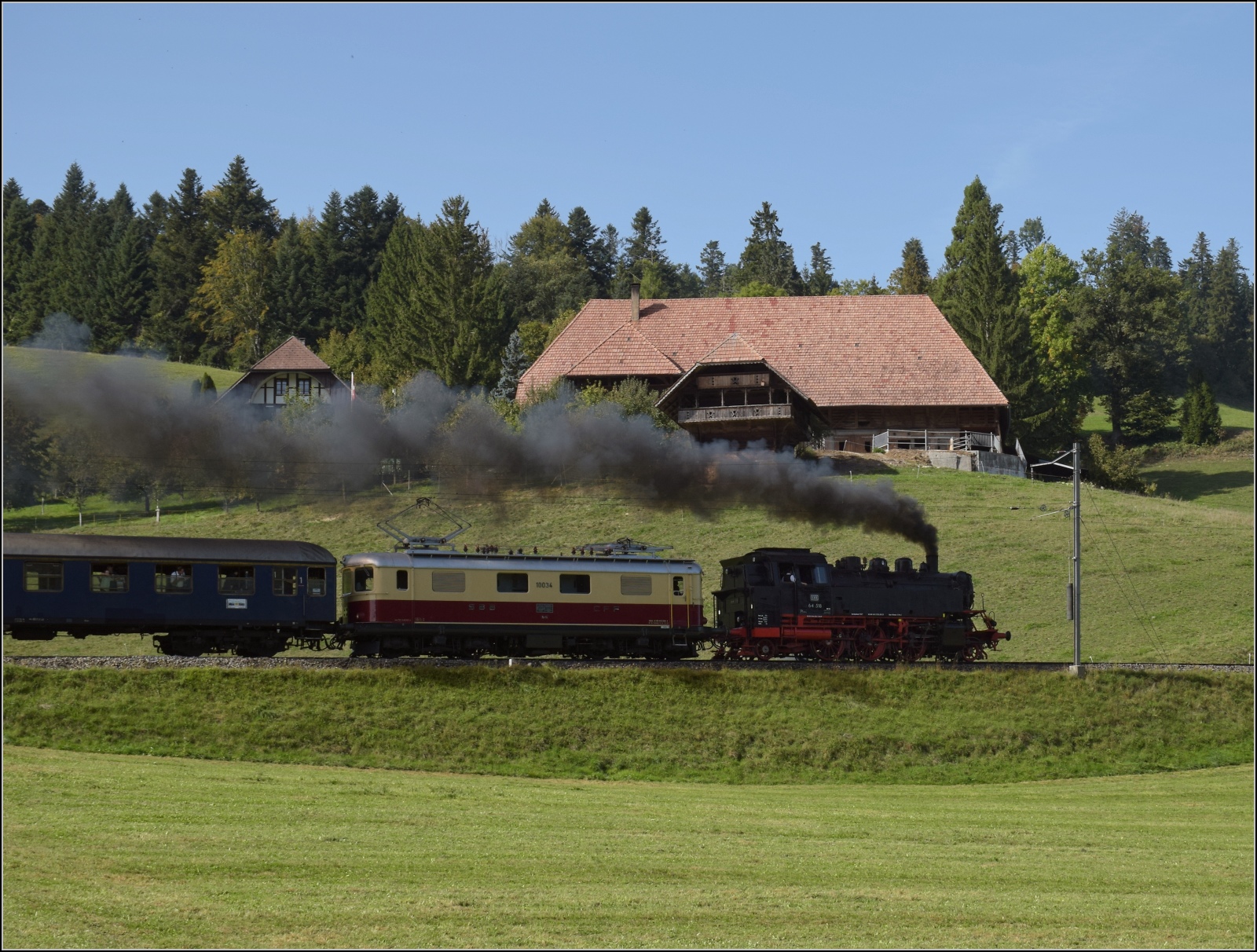 Dampftage Huttwil mit frisch genesenem Bubikopf. 

In Wydithub geht es für 64 518 und Re 4/4 I 10034 die steile Rampe nach Weier hinauf. Oktober 2023.