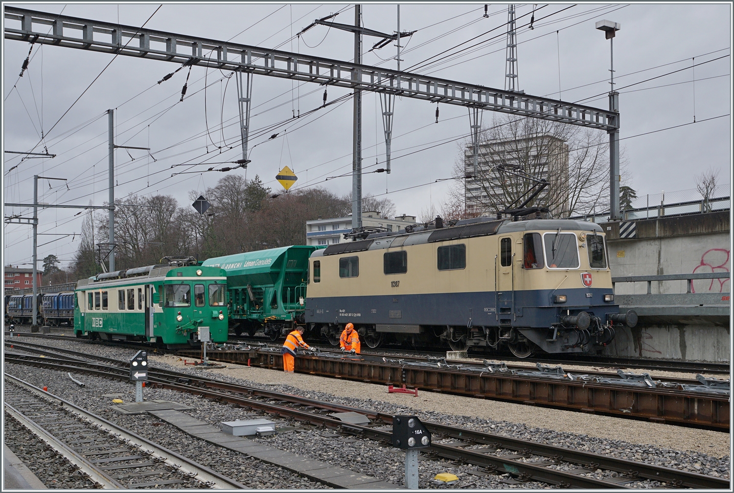 Der Bahnhof von Morges mit zwei besonderen Fahrzeugen: Da die BAM MBC SURF Be 4/4 den Passagierverkehr dominierten, sind die älteren Be 4/4 nun mehr selten zu sehen. Sie werden nach wie vor aber im Güter- und Dienstzu Verkehr eingesetzt. Neben dem Be 4/4 11 der Rollböcke rangiert, ist die IRSI Re 4/4 II 11387 (Re 421 387) zu sehen, wie sie einen Kieszug Galand - Apples auf die Rollbockanlage schiebt.

22. Februar 2024