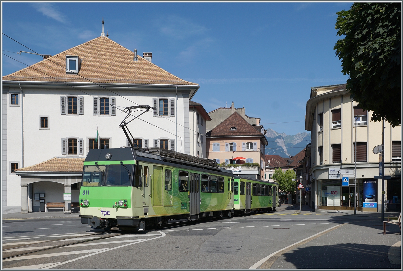 Der BDeh 4/4 311 mit seinem Bt 363 ist auf der Fahrt zum Bahnhof von Aigle und erreicht hier die Altstadt von Aigle, wo das Trasse der Bahn mitten auf der Strasse durch die engen Gassen führt.

27. Juli 2024