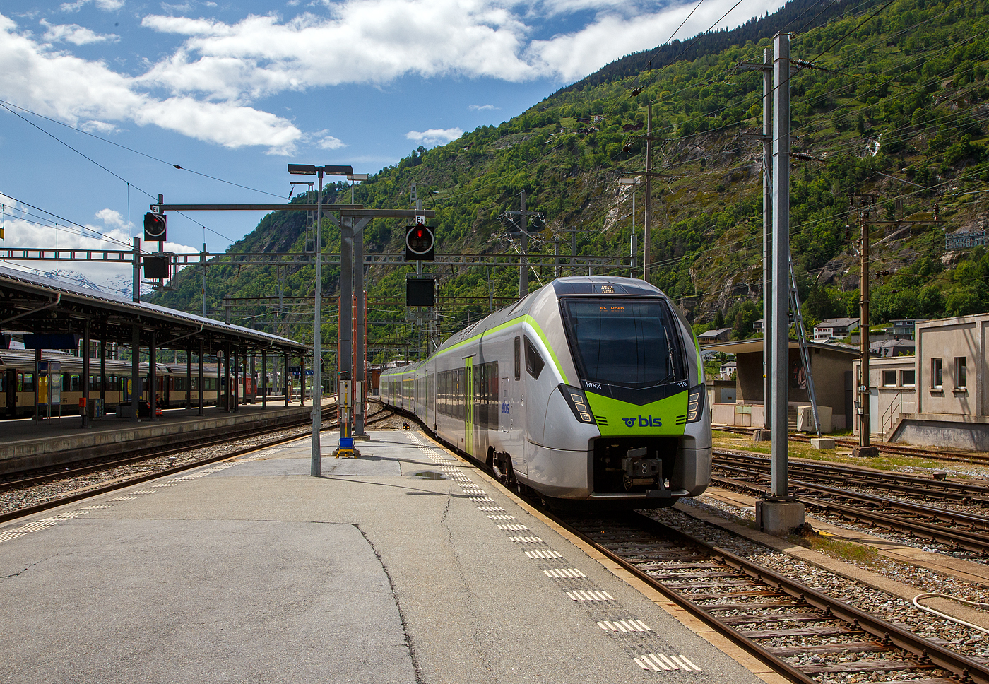 Der BLS MIKA 110 (in Regioexpress-Ausführung) - RABe 528 110 (94 85 7528 110-0 CH-BLS) erreicht am 25 Mai 2023, als RE von Bern via Spiez und Kandersteg nun den Bahnhof Brig (auf Gleis 9). Eigentlich sollten die BLS“MIKA” von Bern über die Lötschberg-Bergstrecke und Brig weiter bis nach Domodossola fahren, aber diese haben noch keine Zulassung für Italien, die sie hinter dem SBB) Simplontunnel bis Domodossola brauchen. Und so wird der Zuglauf in Brig gebrochen und die Reisende, die bis Domodossola wollen, müssen in einen am Gleis 8 bereitgestellten “NINA” umsteigen. 