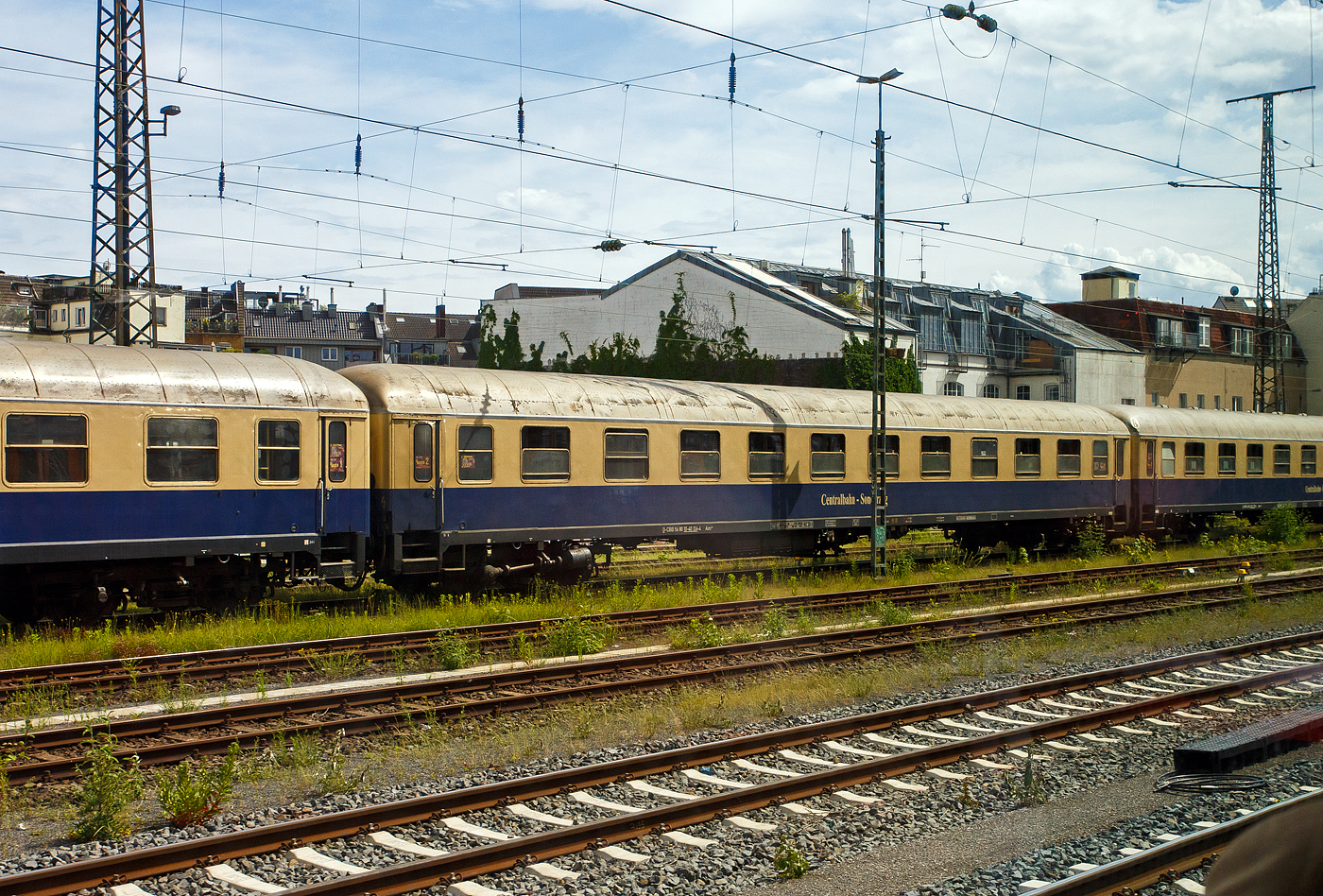 Der erste Klasse Reisezugwagen (Abteilwagen) D-CBB 56 80 10-40 124-4 der Gattung Am 208 der Centralbahn GmbH (Mönchengladbach), eingereiht im Zugverband eines mit 12 Wagen sehr langen Sonder- oder Partyzug der CBB, am 16 Mai 2024 in Köln-West, aufgenommen aus einen Zug heraus.

Der UIC-X-Wagen wurde 1957 von der Waggonfabrik Wegmann & Co. in Kassel gebaut und als DB 11 924 Esn der Gattung A4ümg-54 an die Deutschen Bundesbahn (DB) geliefert. 1966 erfolgte der Umbau und Umzeichnung in D-DB 51 80 10-40 112-4 der Gattung Am 202, im Jahr 1984 wurde er bei Wegmann zum D-DB 51 80 03-40 124-8 Am 036 umgebaut. Im Jahr 1993 wurde er an den EK-Verlag verkauft, 2000ter ging er als D-CBB 56 80 10-40 124-4 Am 208 an die Centralbahn.

Die Wagen der Gattung Am 208 bieten 60 bequeme Sitzplätze in zehn 6er-Abteilen der 1. Wagenklasse, zudem besitzen sie 2 WC/ Waschräume. Dieser Wagen ist für 140 km/h zugelassen und mehrspannungsfähig.

Schnellzugwagen A4ümg-54 DB
Das Bundesbahn-Zentral-Amt (BZA) Minden der Deutschen Bundesbahn (DB) entwickelte um 1952 ein Typenprogramm für 26,4 m-Fernreisezugwagen (Gruppe-53). Unter der Leitung von Dr.-Ing. Adolf Mielich entstand ein als Baukastensystem ausgelegtes Wagen-Programm. Er griff seine Entwürfe aus der Reichsbahnzeit wieder auf, zudem viele moderne Elemente wie die geschlossenen Gummiwulstübergänge und 1.000 bzw. 1.200 mm breite Übersetzfenster. Von den Vorkriegswagentypen unterschied es sich durch gerade Abteilanzahlen und symmetrische Wagenhälften, welche es ermöglichten, gleiche oder unterschiedliche Wagenklassen sowie Speise- und Packräume miteinander zu kombinieren. Nach neun Probewagen im Jahr 1952 begann 1955 die Serienfertigung. Die B4ümg-54 Reisezugwagen (1.225 Stück) boten den Reisenden der 2. Klasse erstmals nur drei Sitze pro Bank, statt bisher vier. Diese Komfortverbesserung bei dem „Reisezugwagen fürs Volk“ kam bei den Fahrgästen sehr gut an. Die erstklassige Wagenbauart A4ümg-54 (199 Stück) unterstrich beispielhaft den gestiegenen Reisekomfort jener Zeit. In eleganter, dunkelblauer Lackierung verließen die Wagen die Werke und wurden vorrangig in die F-Zugverbände der DB eingereiht. Vervollständigt wurde die Wagengruppe-53 durch die gemischt-klassigen AB4ümg-55 (357 Stück) und ab dem Ende der 1950er-Jahre durch die Halbgepäckwagen der Bauart BPw4üm-58/59 (138 Stück). Durch ihre wegweisenden Neuerungen waren die Wagen, und die aus Ihnen abgeleiteten späteren Umbauten, für die kommenden Jahrzehnte nicht aus den Reisezügen der DB wegzudenken. So verwundert es nicht, dass die letzten Wagen teilweise erst zu Beginn in den 1990er-Jahre ausgemustert wurden, oder dann ein zweites Leben im Museumsverkehr begannen.

TECHNISCHE DATEN:
Spurweite: 1.435 mm (Normalspur)
Länge über Puffer: 26.400 mm
Wagenkastenlänge: 26.100 mm
Wagenkastenbreite: 2.850  mm
Höhe über Schienenoberkante: 4.050 mm
Drehzapfenabstand: 19.000 mm
Achsstand im Drehgestell: 2.500 mm
Drehgestellbauart: Minden-Deutz 330
Leergewicht: 37 t
Höchstgeschwindigkeit: 140 km/h
Sitzplätze in der 1. Klasse: 60
Abteile: 10
Toiletten/Waschraum: 2 
Bremsbauart: KE-GPR
Energieversorgung: Achsgenerator

Die Centralbahn GmbH (Mönchengladbach) gehört zur Centralbahn AG mit Sitz in Basel. Hauptgeschäft ist die Durchführung von Sonderzugfahrten mit eigenen Fahrzeugen.