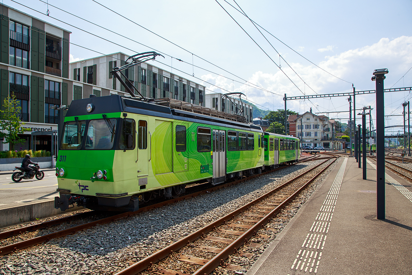 Der Triebwagen mit Gepckabteil BDeh 4/4 311 (ex 303)  „Yvorne“ und der Steuerwagen Bt 361 (ex 353) beide der tpc (Transports Publics du Chablais), ex bzw. Betriebsteil AL - Aigle-Leysin-Bahn, stehen am 28 Mai 2023 im Schmalspur-Bahnhof Aigle. Auch dieser Pendelzug trgt nun die neue TPC-Lackierung und nicht mehr die ursprngliche Lackierung der AL (creme-braun), nach der Neulackierung wurden auch nicht mehr die Wappen der Triebwagen angebracht.

Der Trieb- und Steuerwagen wurde 1987 von Vevey - Ateliers de constructions mcaniques de Vevey (ACMV) gebaut, die SLM (Schweizerischen Lokomotiv- und Maschinenfabrik) in Winterthur lieferte die Drehgestelle mit der Zahnradtechnik und die BBC (Brown, Boveri & Cie.) die elektrische Ausrstung. Die ehemalige Fabrikhalle der ACMV steht heute noch in Vevey, siehe: http://hellertal.startbilder.de/bild/schweiz~hersteller~vevey-acmv-spaeter-vevey-technologies-sa/814732/die-ehemalige-fabrikhalle-des-1842-gegruendeten.html

Die Triebwagen BDeh 4/4 311 bis 313 (ex 303 bis 305) sind meterspurige elektrische Personentriebwagen mit Gepckabteil fr gemischten Zahnrad- und Adhsionsbetrieb (Zahnstangensystem Abt). Der Pendelzug (BDeh 4/4 mit Bt) besitzt nur die 2. Wagenklasse auf eine 1. Wagenklasse wurde verzichtet. 

Anfang der 1980er Jahren prsentierte sich das Rollmaterial der AL zwar in einem guten Zustand, doch gengte es den Komfortansprchen nur noch bedingt. Da auch die drei anderen Bahnen der TPC neues Rollmaterial bentigten, wurde ein gemeinsames Beschaffungskonzept erarbeitet. Schlielich fand im sechsten Rahmenkredit fr Privatbahnhilfe des Bundes auch eine Rollmaterialbestellung fr AL, AOMC und BVB Platz. 1984 wurden insgesamt drei neue Pendelzge fr die AL (2 Stck) und die BVB (1 Stck) bei ACMV, SLM und BBC in Auftrag gegeben. Die bei der AL als BDeh 4/4 303-304 bezeichneten Fahrzeuge stellen eine Weiterentwicklung der BVB BDeh 4/4 81-82 dar und wurden mit 4 x 209 kW motorisiert. Wie die BDeh 4/4 301-302 haben sie eine Maximalgeschwindigkeit von 40 km/h, was aber fr die AL-Verhltnisse gengt. Gleichzeitig mit den Triebwagen wurden 1987 auch zweipassende Steuerwagen Bt 353-354, die vom CEV Bt 223 abgeleitet wurden, in Betrieb genommen.

Mit den neuen Pendelzgen hielt auch ein neues Erscheinungsbild bei der TPC Einzug. Die Fahrzeuge aller vier Eisenbahngesellschaften wurden in einheitlichem Design gestaltet, wobei die bahneigenen Farben beibehalten werden konnten (creme-braun fr die AL). Ab 1989 hielt dieser Anstrich auch bei den brigen Fahrzeugen der AL Einzug. 1993 wurde mit dem BDeh 4/4 305 und Bt 355 ein weiterer, praktisch baugleicher Pendelzug in Betrieb genommen.  Im Jahr 2002 erfolgte die Umzeichnung der Triebwagen BDeh 4/4  303 bis 305 in BDeh 4/4 311 bis 313, sowie der Steuerwagen Bt 353 bis 355 in Bt 361bis 363.

Auch wenn Triebwagen zusammen mit den Steuerwagen als Pendelzge konzertiert sind, so haben die Triebwagen trotzdem zwei Fhrerstnde und knnen so auch alleine in beide Richtungen fahren.

TECHNISCHE DATEN:
Hersteller: (1987/1993) ACMV/SLM/BBC
Baujahr: 1987 (2 Stck) / 1993 (1Stck)
Spurweite: 1.000 mm
Fahrleitungsspannung: 1.500 V =
Maximale Streckenneigung: Adhsion 38 ‰ / Zahnstange 230 ‰
Zahnstangensystem: Abt

TRIEBWAGEN:
Typ und Nummerierung: BDeh 4/4 311 – 313 (bis 2002 ex 303 bis 305)
Achsfolge: Bo'zz Bo'zz
Lnge ber Puffer: 15.400 mm
Leistung: 4 x 209 kW = 836 kW (1.136 PS)
Hchstgeschwindigkeit: 40 km/h (Adhsion) / 25 km (Zahnrad)
bersetzung: 1:12,2
Gewicht: 35.8 t
Sitzpltze: 32
Stehpltze: 29
Max. Ladegewicht: k.A.

STEUERWAGEN:
Typ und Nummerierung: Bt 361–363 (bis 2002 ex Bt 353–355)
Anzahl der Achsen: 4
Gewicht: 10,0 t
Sitzpltze: 40
Stehpltze: 72