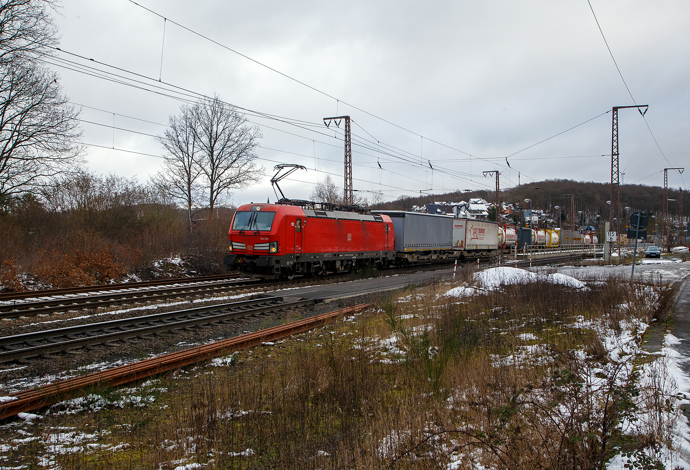 Die 193 323-3 (91 80 6193 323-3 D-DB) der DB Cargo AG fährt am 27.01.2023 mit einem „HUPAC“ KLV-Zug durch Rudersdorf (Kr. Siegen) in Richtung Siegen. Hier befährt der Zug die Dillstrecke (KBS 445) von dieser geht es bei Siegen-Ost auf die Siegstrecke (KBS 460) in Richtung Köln. Weil die Ruhr-Sieg-Strecke (KBS 440) nicht das KV-Profil P/C 400 aufweist, sind solche Züge dort nur bis Kreuztal zum Südwestfalen Container-Terminal möglich.

Die Siemens Vectron MS (200 km/h - 6.4 MW) wurden 2018 von Siemens unter der Fabriknummer 22448 und gebaut, sie hat die Zulassungen für Deutschland, Österreich, Schweiz, Italien und die Niederlande (D/A/CH/I/NL).