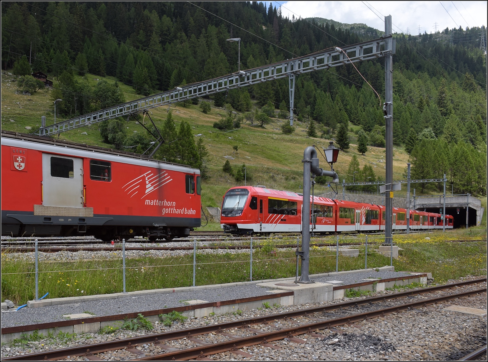 Die Ablösung macht sich parat: ABeh 8/12 Orion.

ABeh 8/12 301 und ABeh 8/12 302 begegnen auf ihrer Testfahrt dem Deh 4/4 I 54 'Goms' in Oberwald (im Goms). Juli 2023.