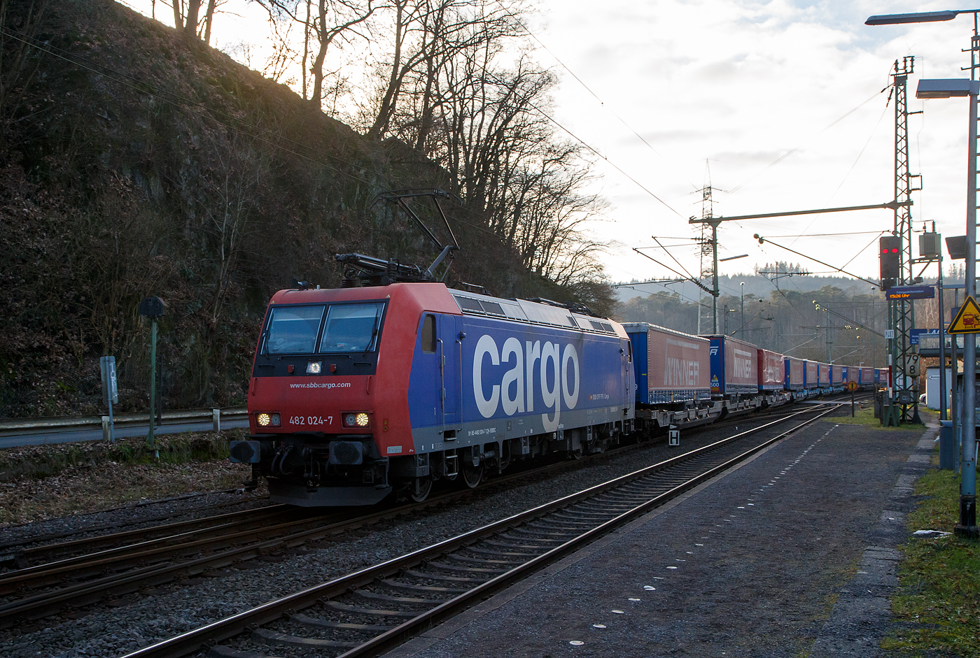 Die an die SBB Cargo International AG vermietete SBB Cargo Re 482 024-7 (91 85 4482 024-7 CH-SBBC) fährt am 28.01.2023 mit einem „Winner“ KLV-Ganzzug durch Scheuerfeld (Sieg) in Richtung Siegen.

Die TRAXX F140 AC1 wurde 2003 von Bombardier in Kassel unter der Fabriknummer 33590 gebaut und an die SBB Cargo AG geliefert. Sie hat die Zulassungen für die Schweiz und Deutschland. Wobei durch das fehlende ETCS ist der Einsatz in der Schweiz nur bedingt möglich, so sieht man sie hauptsächlich in Deutschland auf der Strecke zwischen Köln und Basel. Einige SBB Cargo Re 482 sind auch bereits verkauft worden.
