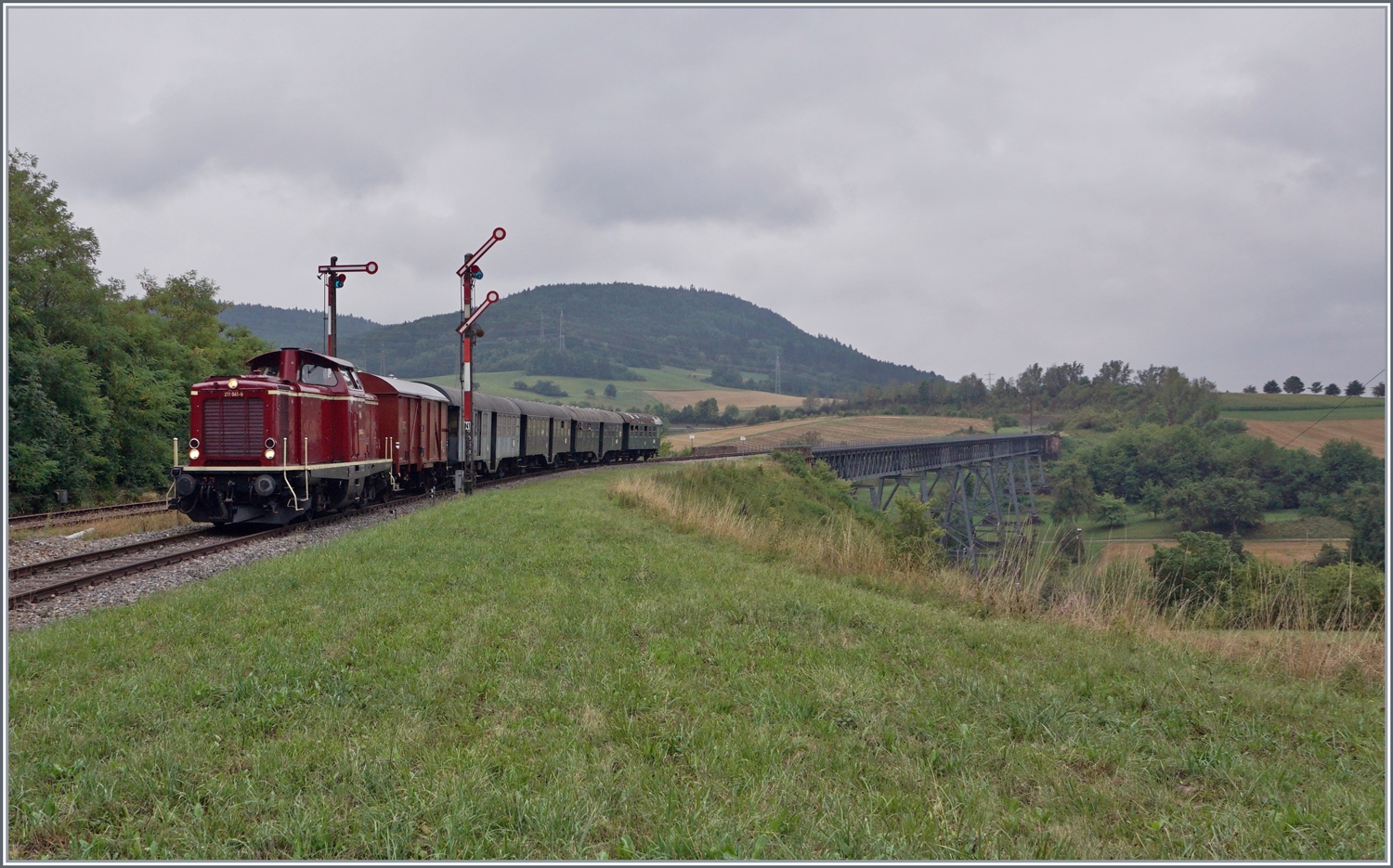 Die Diesellok 211 041-9 (92 80 1211 041-9 D-NeSA) hat mit ihrem  Morgenzug  die Talbergang Epfenhofen Brcke berquert und erreicht nun den Bahnhof Epfenhofen. Die Talbergang Epfenhofen Brcke ist mit 264 Meter Lnge die lngste Brcke der Sauschwnzlebahn. 

27. August 2022