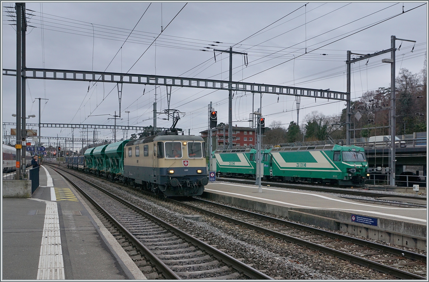 Die IRSI  Rheingold  Re 4/4 II 11387 (Re 421 387) ist mit ihrem Kieszug in Morges angekommen. Die Lok wird den Zug nun vorziehen und in der Folge über die Rollbockanlage zurückschieben. Die Rollbockanlage befindet sich bei den beiden auf Zug warteten BAM MBC  Ge 4/4 21 und 21, die jedoch ebenfalls noch am Rangieren sind, da sie ihrerseits einen Kieszug aus Apples nach Morges brachten.

4. März 2024