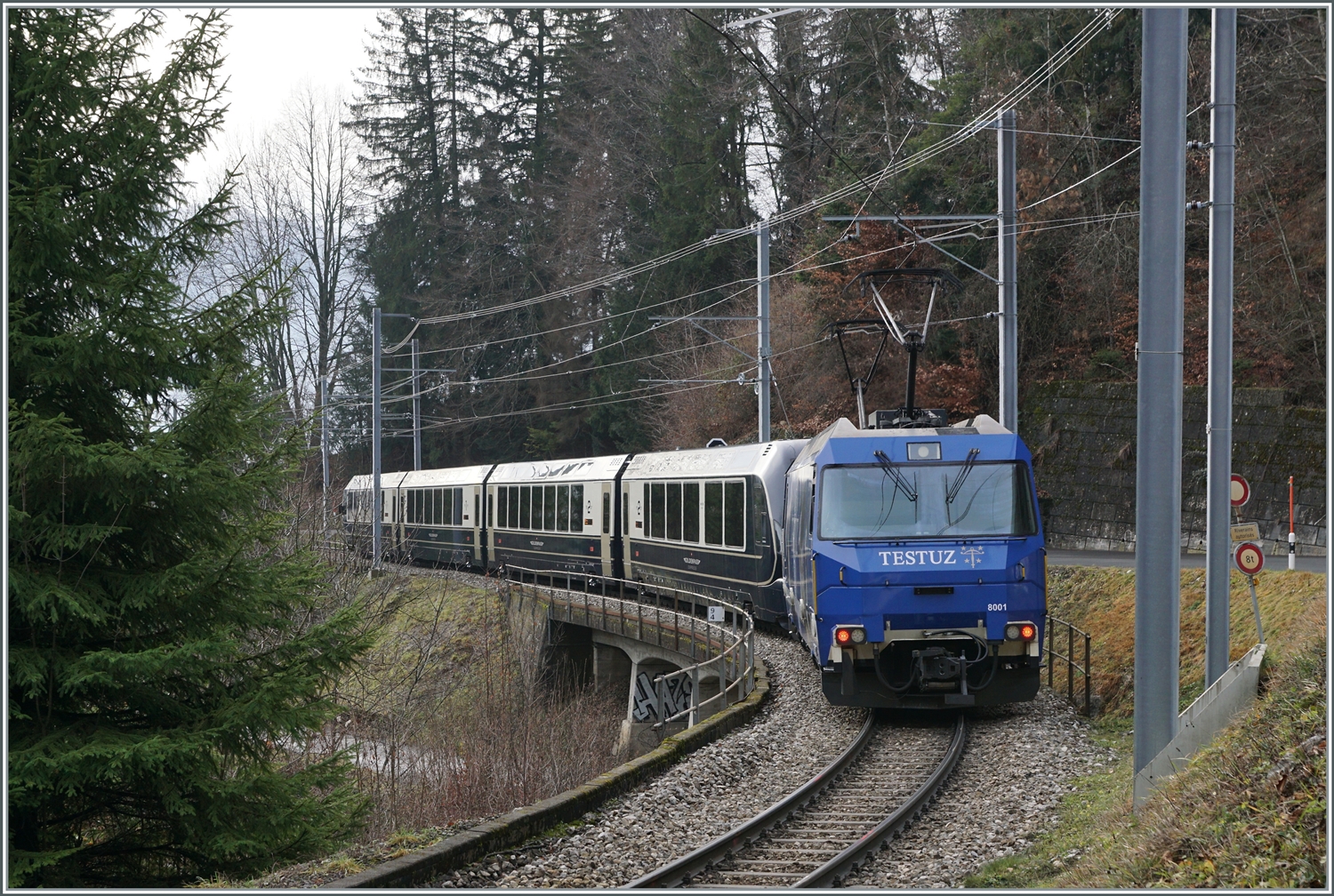 Die MOB Ge 4/4 8001 ist als Schublok mit dem GoldenPass Express 4065 von Interlaken nach Montreux unterwegs. Die Ge 4/4 8001 hat den Zug in Zweisimmen übernommen und rollt nun kurz nach der 93 Meter langen Pont Gardiol, welche den Bois des Chenaux überbrückt, ihrem Ziel Montreux entgegen.

4. Januar 2023 