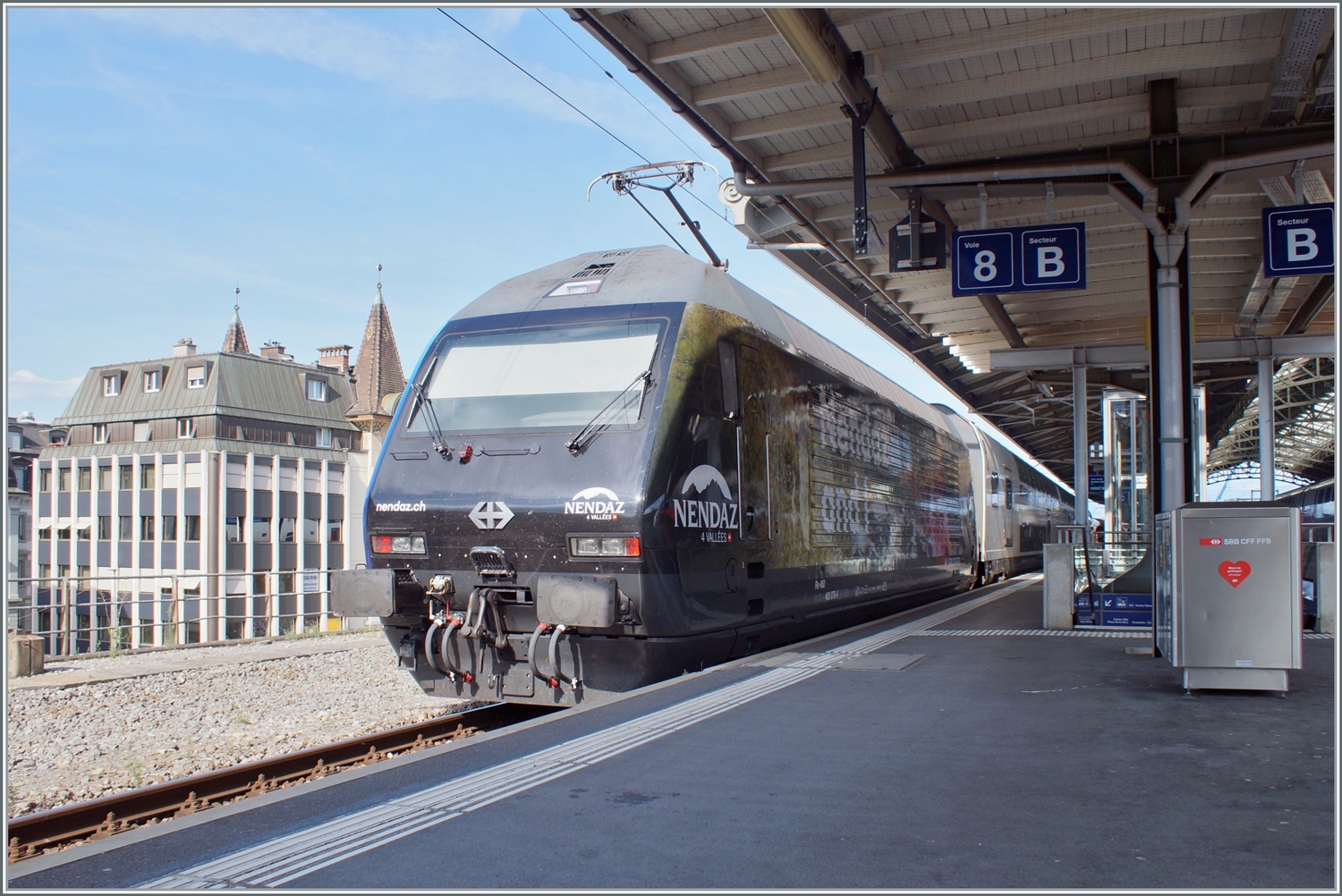 Die neue Werbelok  NENDAZ 4 vallée  460 078 (91 85 4 460 078-9 CH-SBB) an einer nicht gerade fotogenen Stelle in Lausanne am Schluss ihres IR 90 von Brig nach Genève Aéroport. 

28. Juli 2023