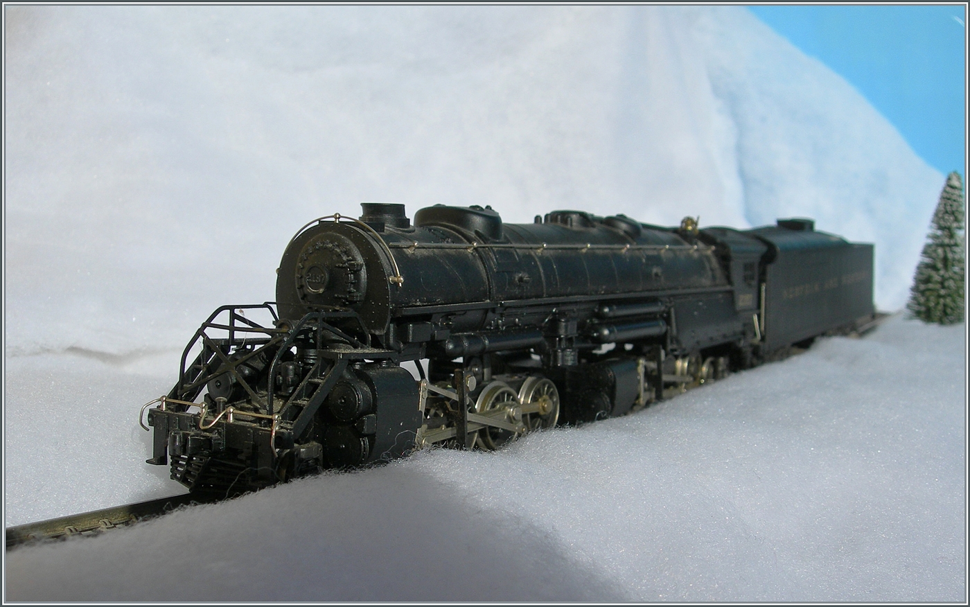 Die selbst in H0 mächtige Mallet Dampflok 2-8-8-2 - Y6b 2197 der Norfolk & Western kämpft sich durch den Schnee. Die Konstruktion der Mallet Vorbildloks Loks basiert Angaben, welche die U.S.R.A. (United States Raitroad Administration) während des Ersten Weltkriegs eingeführt hat. Die die Loks der Klasse Y6b wurde ab 1936 ausgeliefert. Grundsätzlich wurde die Klasse Y6b so konstruiert, dass sie schwere Güterzug mit 30 mp/h ziehen konnte, doch unter guten Bedingungen konnten auch bis zu 50 mp/h erreicht werden. 

Das Modell dieser Gelenklokomotive Typ Mallet „Y 6 b“ der  Norfolk & Western  dürfte gut 50 bis 60 Jahre alt sein und ist eine von der Grüsse her sehr beeindruckende Modellumsetzung. Nicht ganz logisch scheint mir, weshalb der Motor bei soviel Platz in das Führerhaus gequetscht wurde, um dann durch lange kardanischen Wellen die weit entfernten  Drehgestelle  anzutreiben. Der Tender ist vorbildgerecht mit zwei dreiachsigen  Buckeye -Drehgestellen ausgestattet, die auch zur Stromabnahme herangezogen werden. 

Das Modell dürfte gut zwanzig bis dreissig Jahre lang nicht mehr gefahren sein, nachdem ich das Modell zerlegt und bewegliche Teile entfettet und neu eingeölt habe, fährt es seit gestern wieder, auch wenn mir für den Auslauf des mächtigen Modell sowohl die Wagen als auch die Strecke fehlt. 

12. Jan. 2025