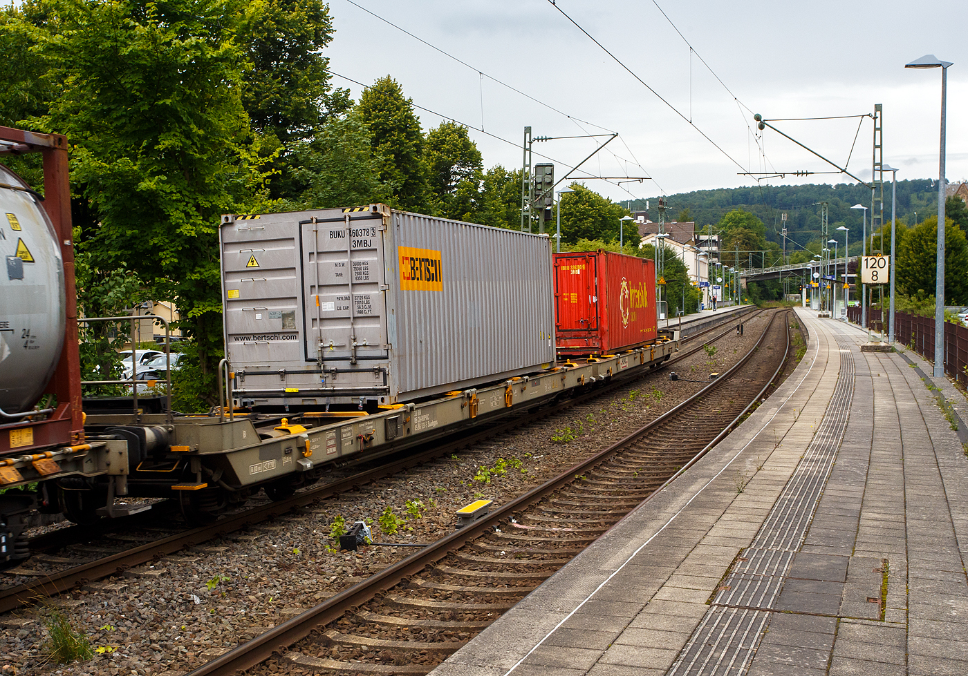 Eher ein Exot unter den Taschenwagen, der niedriggelegte achsachsige Doppelwagen Mega I, 33 85 459 6 036-5 CH-HUPAC, der Gattung Saadggns, der HUPAC Intermodal SA (Chiasso), am 01 August 2025 im Zugverband bei einer Zugdurchfahrt im Bahnhof Kirchen/Sieg, hier beladen mit zwei 30`-Container. Die Wageneinheit ist über eine sogenannte Kurzkupplung realisiert. So ist es einer 2x4-achsigen Wageneinheit, also vier Drehgestellen (acht Achsen) pro Wageneinheit.

Diese Wagen wurden in einer Serie von 45 Stück 1994 von der Ferriere Cattaneo SA in Giubiasco (Tessin/CH). Leider sind im Netz keine Datenblätter vorhanden, so kann ich den Wagen nur nach den Anschriften und eigener Sichtung beschreiben.

Diese Güterwagen sind zum Transport von kranmanipulierbaren Sattelaufliegern und genormten Wechselbehältern / Containern an allen europäischen Eisenbahnstrecken mit Normalspurweite bestimmt, auch bekannt als intermodaler Verkehr. Durch die niedrig gelegte Ladefläche können C 70-400 kodifizierte Jumbo-Wechselbehälter bis Norditalien und High-Cube-Container bis Süditalien auf der Gotthardstrecke transportiert werden.

TECHNISCHE DATEN:
Spurweite: 1.435 mm (Normalspur)
Länge über Puffer: 35.570 mm
Drehzapfenabstände: 13.300 mm /4.940 mm / 13.300 mm
Achsabstand in den Drehgestellen: 1.800 mm
Laufraddurchmesser: 840 mm (neu)
Ladelänge: 2 x 15.850 mm (ca. 2 x 52`)
Höhe der Ladeebene für Container/WB über SOK: 940 mm
Höhe der Tasche (für Sattelanhänger) über SOK: 270 mm
Eigengewicht: 33.000 kg
Max. Zuladung: 92,0 t (ab Streckenklasse A)
Max. Gewicht eines Sattelanhängers (je Wageneinheit): 38,5 t
Höchstgeschwindigkeit: 100 km/h (beladen) / 120 km/h (leer)
Bremse: O-GP-A (K) – 2 x 46 t
Bremssohle: Jurid 838 (Komposit-Bremssohlen)
Feststellbremse: Ja, jeweils an den mittleren Drehgestellen
Kleinster befahrbarer Gleisbogen: R 80 m
Verwendungsfähigkeit: RIV (Regolamento Internazionale Veicoli)

Die Bedeutung der Gattungs- und Kennbuchstaben (hier Saadggns):
S - Drehgestell-Flachwagen in Sonderbauart
aa - mit acht oder mehr Radsätzen
d - für den Transport von Straßenfahrzeugen eingerichtet
gg - für den Transport von Containern über 60 Fuß eingerichtet
n - mit sechs oder mehr Radsätzen höchste Lastgrenze über 75 
s - Höchstgeschwindigkeit (beladen) bis zu 100 km/h
