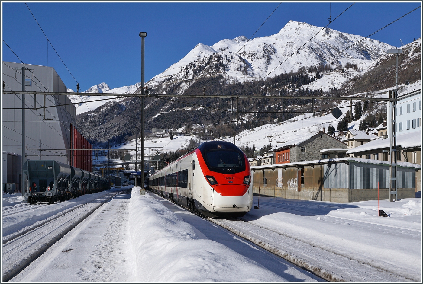 Ein SBB RABe 501  Giruno  rollt leise durch den verschneiten Bahnhof von Airolo in Richtung Süden. 

21. Jan. 2025