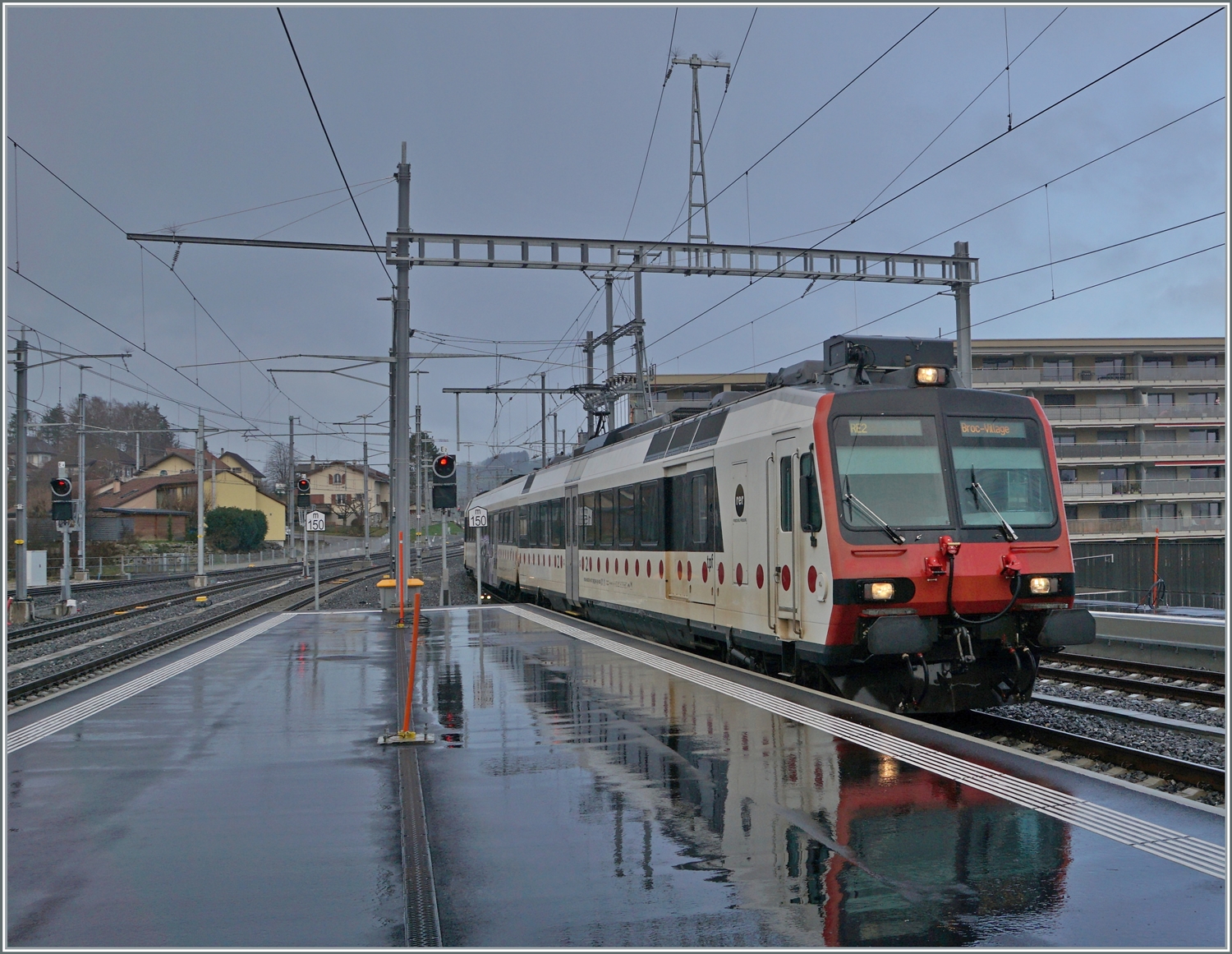 Ein TPF Regionalzug nach Broc Village (und sein Spiegelbild) erreichen Bulle. 

22. Dez. 2022