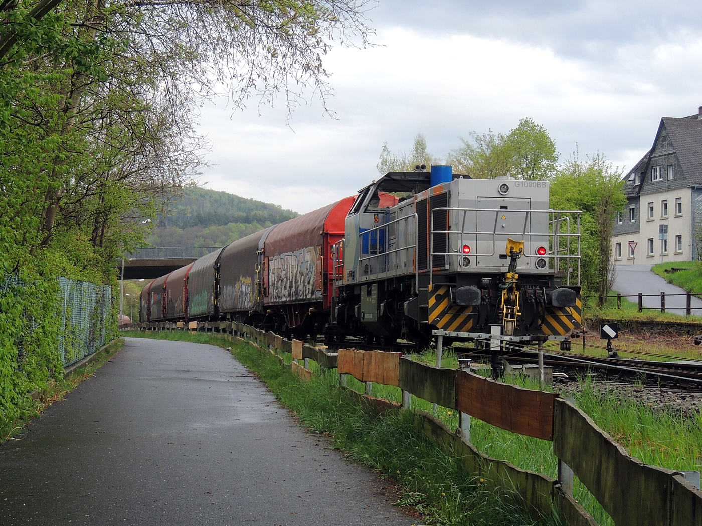 Hochbetrieb in Herdorf am 23 April 2025: 
Durch die vergangenen Osterfeiertage braucht es wohl wieder Nachschub. Die KSW (Kreisbahn Siegen-Wittgenstein) kommt im Sandwich mit einem sehr langen und somit schweren Coilzug, von via Betzdorf/Sieg kommend, und erreicht den KSW-Rangierbahnhof (Betriebsstätte FGE - Freien Grunder Eisenbahn).

Hier am Zugschluss die nachschiebende KSW 47 (92 80 1271 027-5 D-KSW), ex D 2 der HFM, eine Vossloh G 1000 BB, vorne als Zuglok die KSW 44 (92 80 1271 004-4 D-KSW) auch eine MaK G 1000 BB. Im Rbf wird der Zug geteilt, da er für die Weiterfahrt sonst zu lang wäre, und die KSW 44 zieht den ersten Teil weiter zu den Schäfer Werke KG am Pfannenberg in Neunkirchen-Salchendorf. 

Die KSW-Bahnstrecke Herdorf–Pfannenberg-(ehem. Unterwilden) ist eine rund 8 km lange Nebenbahn, bekannt ist sie auch als „Talbahn“. Die Strecke wurde von der 1904 gegründeten Freien Grunder Eisenbahn AG betrieben. Die gebliebenen Gleise und Anlagen sind seit 1970, als Betriebsstätte FGE - Freien Grunder Eisenbahn. Teil der heutigen Kreisbahn Siegen-Wittgenstein.

Später kam dann noch die KSW 43 (92 80 1273 018-2 D-KSW), die asymmetrische Vossloh G 2000 BB, mit einem langen Coilzug von Duisburg an.