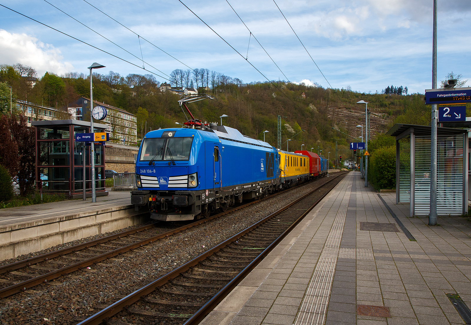In einer ungewöhnlichen Komposition (im Sandwich zweier SIEMENS Vectron Dual Mode) fährt ein Schienenprüfzug (SPZ 3), auf Prüffahrt (der Messwagen ist auf die Schiene absenkt) am 30.04.2023 durch den Bahnhof Kirchen an der Sieg in Richtung Siegen. 

Die vierteilige Komposition bestand aus:
• Der SIEMENS Vectron Dual Mode der 248 027-5 (90 80 2248 027-5 D-PRESS) alias 248 106-8 der PRESS (Eisenbahnbau- und Betriebsgesellschaft Pressnitztalbahn mbH, Jöhstadt).
• Dem Messwagen SPZ-STW (STW steht für Steuerwagen) 720 301(99 80 9360 006-7 D-DB) der DB Netz AG (Netz Instandhaltung/Fahrwegmessung).
• Einem Hilfszug-Wagen (Nummer unbekannt) der DB Netz AG (Notfalltechnik).
• Und der SIEMENS Vectron Dual Mode der 248 026-7 (90 80 2248 026-7 D-PRESS) alias 248 105-9 der PRESS (Eisenbahnbau- und Betriebsgesellschaft Pressnitztalbahn mbH, Jöhstadt).

Die Energieversorgung vom Messwagen und dem Hilfszug-Wagen erfolgte von den Loks (spartanisch) über außenverlegte Kabel, zudem waren beide Loks über eine außenliegende Steuerleitung verbunden. Normalerweise ist der Schienenprüfzug ein zweiteiliger Messtriebwagen, bestehend aus Trieb- (ATW - 719 301) und einem Steuerwagen (STW - 720 301), siehe u.a. http://hellertal.startbilder.de/bild/Deutschland~Unternehmen~DB+Netz+AG/773623/der-plasser--theurer-schienenpruefzug-der.html Warum es nun diese Komposition ist, das ist mir nicht bekannt, vielleicht setzt man nun noch mehr auf E-antrieb.

Der Schienenprüfzug wurde 2015 von Plasser & Theurer in Linz (A) unter der Fabriknummer 6003 (SPZ-STW) gebaut. Um Schäden am Oberbau frühzeitig zu erkennen, setzt die Deutsche Bahn AG verschiedene Prüfzüge der Baureihen 719 und 720 ein. Mittels zweier zerstörungsfreier Prüfverfahren werden die Schienen auf Schädigungen untersucht. Bei der Ultraschallprüfung können Materialfehler durch Materialermüdung innerhalb der Schiene bis zum Schienenfuß erkannt werden. Mit der Wirbelstromprüfung wird der Schienenkopf geprüft.

Die beiden SIEMENS Vectron Dual Mode wurden 2022 von SIEMENS in München-Allach, unter den Fabriknummern 23168 und 23169, gebaut und an die PRESS - Eisenbahnbau- und Betriebsgesellschaft Pressnitztalbahn mbH in Jöhstadt geliefert. Die beiden Vectron DM haben die Zulassung in Deutschland für eine Höchstgeschwindigkeit 160 km/h.

Der Vectron Dual Mode vereint die Vorteile einer vollwertigen Diesellokomotive mit denen von elektrischen Lokomotiven. Dank des leistungsstarken Dieselantriebs sowie der Ausstattung für die Nutzung der Fahrleitung kann man jederzeit flexibel auf die Traktionsanforderungen reagieren. So bleibt man immer in Bewegung, egal ob mit oder ohne Fahrdraht. Wo ein Fahrdraht ist, sollte man ihn nutzen. Denn der Betrieb unter Oberleitung ist im Vergleich zum Dieselbetrieb deutlich kosteneffizienter und umweltfreundlicher. Doch weil es in Deutschland noch lange Zeit Strecken geben wird, die nicht vollständig elektrifiziert sind, fahren viele Diesellokomotiven unter Fahrdraht weiter. Das ist aber ökonomisch und ökologisch wenig sinnvoll. Dies ist hier ein Beispiel einer echten Alternative.