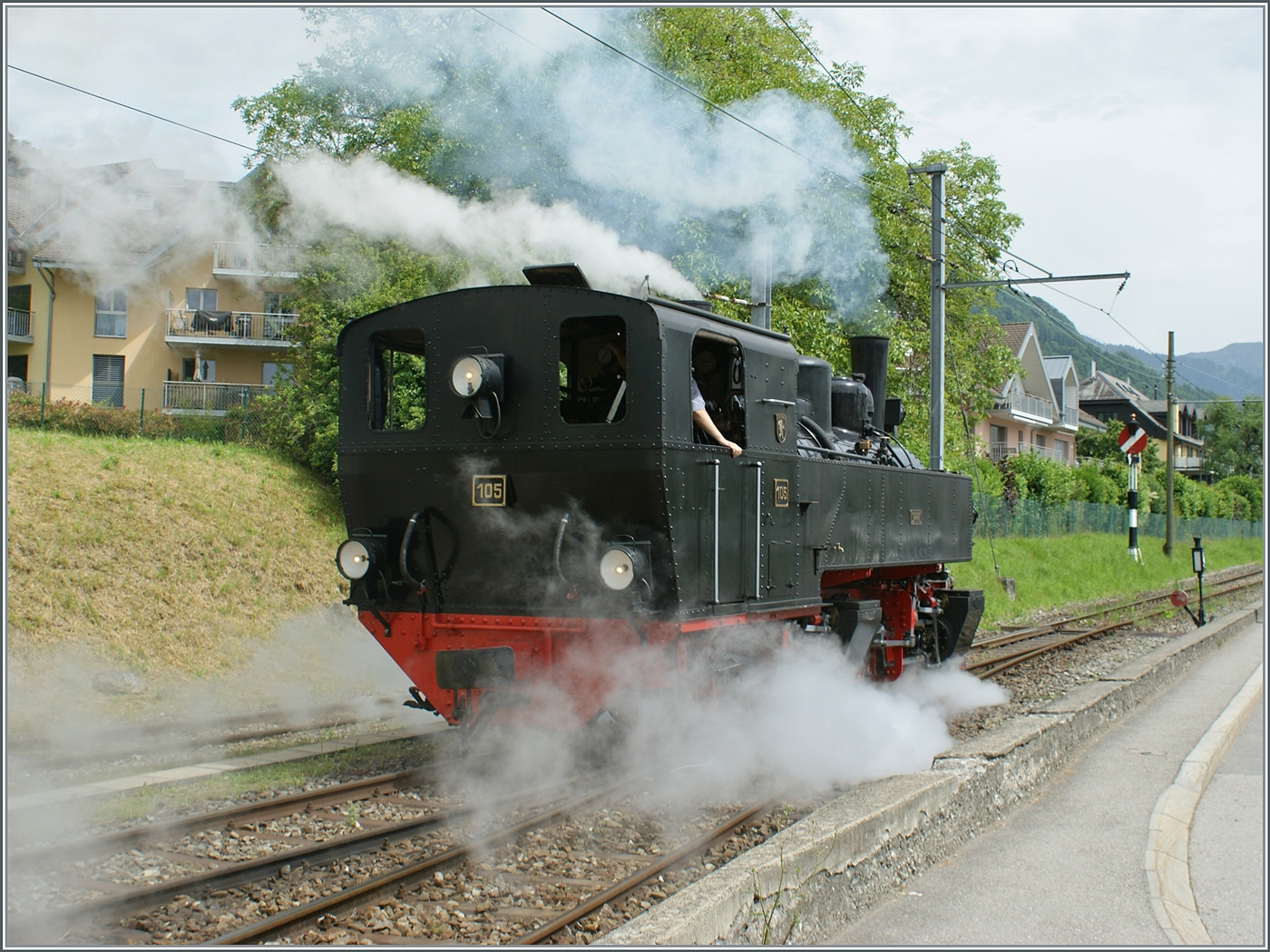 Kräftig dampfend rangiert die SEG G 2x 2/2 105 der Blonay Chamby Bahn in Blonay um ihren Zug zu umfahren. Gerade  schlechtes Wetter  bietet oft ganz besondere Motive, so dass sich eine Museumsbahnbesuch auch bei Regen lohnt. 09. Juni 2024