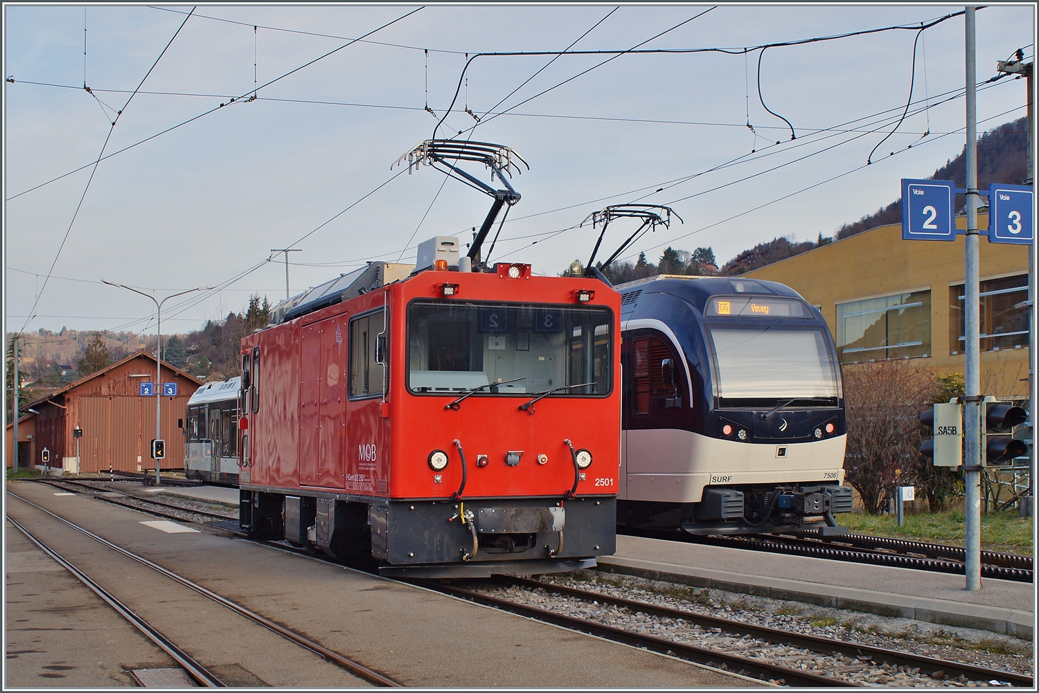 MOB HGem 2/2 2501 (ex CEV MVR) und CEV MVR ABeh 2/6 7506 in Blonay; während der HGem 2/2 sich auf einer Schulungsfahrt befindet, wartet der SURF auf die Abfahrt nach Vevey.

31. Jan. 2024