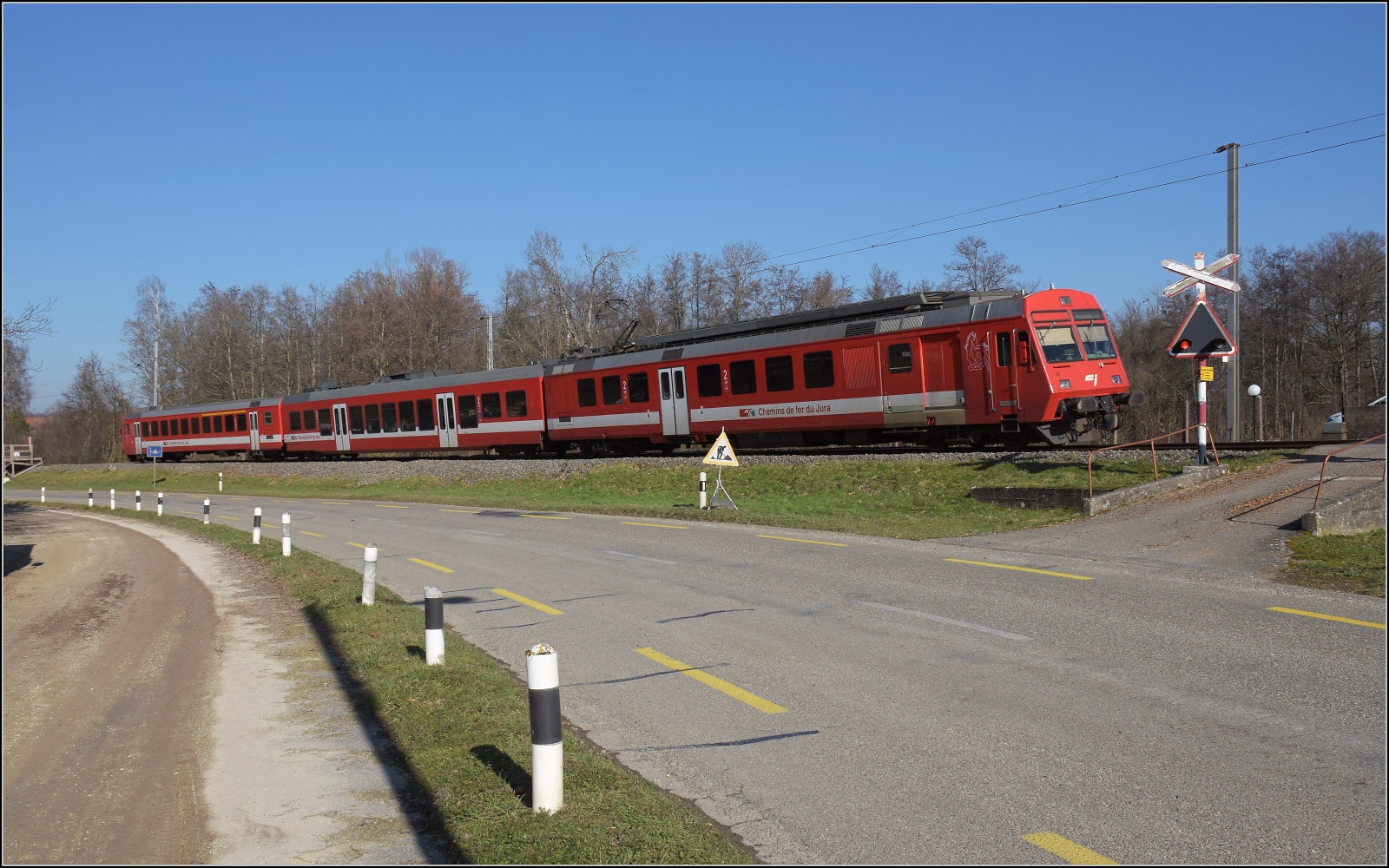 Noch ein bisschen Ajoie.

RABe 567 184 der CJ an einem kleinen altertmlichen Bahnbergang vor Bonfol. Februar 2023.