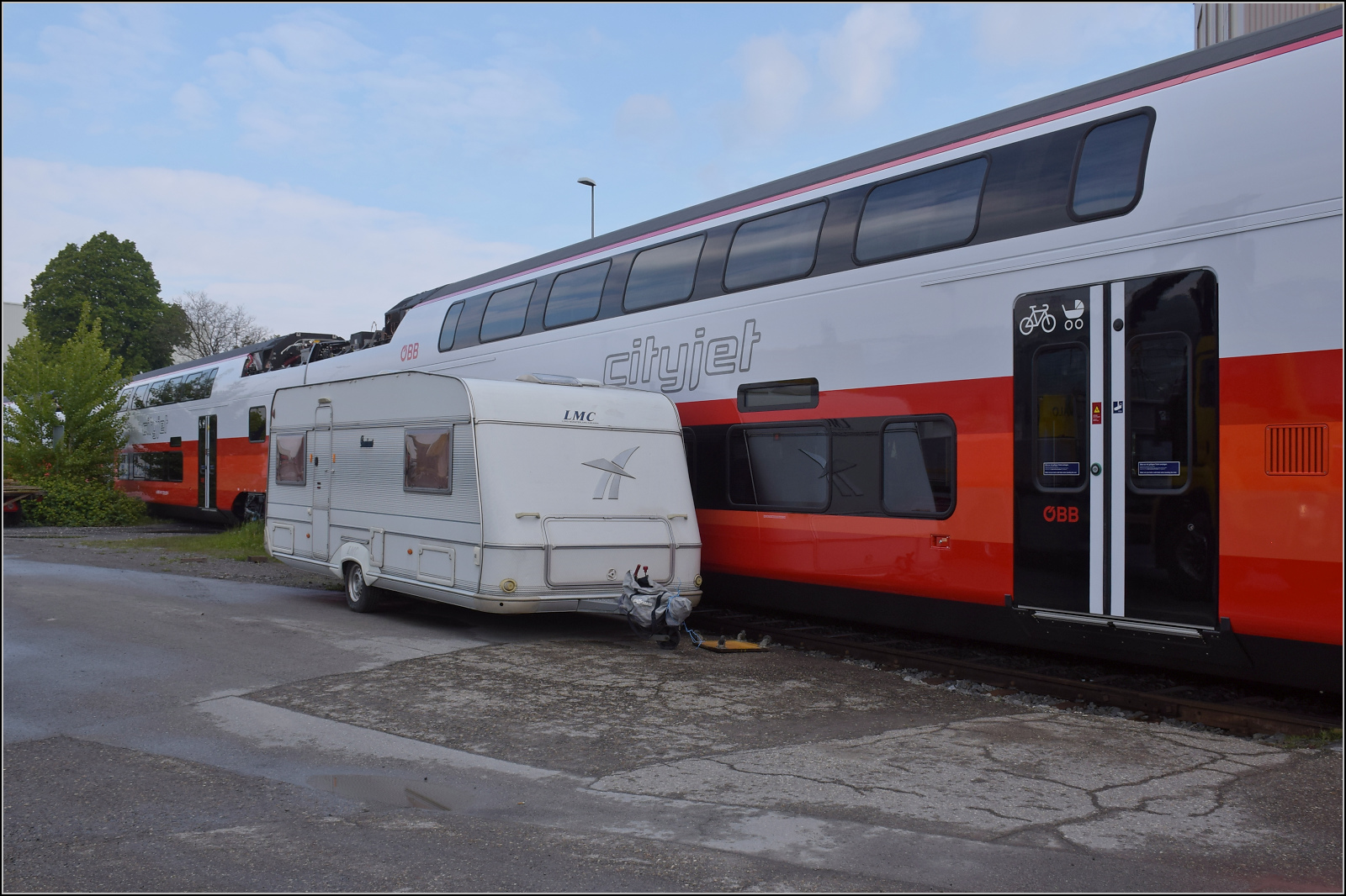 Rollout des ersten Kiss für die ÖBB.

Ziemlich knapp geht es erst mal an einem ungünstig abgestellten Wohnwagen vorbei, hier für den Zwischenwagen 7034 301. St. Margrethen, April 2024. 