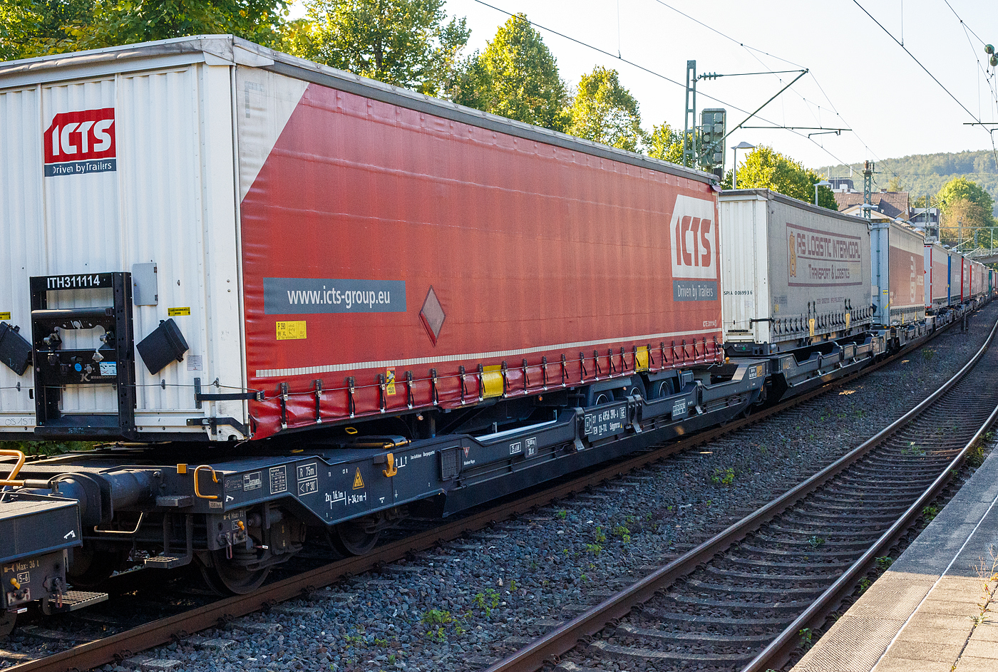 Sechsachsiger Gelenk-Taschenwagen (Doppeltaschenwagen T3000e), 37 85 4956 390-6 CH-TXL, der Gattung Sdggmrss (T3000e), der TX Logistik AG (Troisdorf), am 17 September 2024 im Zugverband bei der Durchfahrt im Bahnhof Kirchen (Sieg), hier beladen mit zwei Sattelanhängern (Trailer). Die TXL gehört seit 2017 zu 100 Prozent der Mercitalia Gruppe, einer Tochtergesellschaft der Ferrovie delle Stato Italiane.

Diese Wagen vom Typ T3000e wurde von Tatravagónka a.s. in Poprad (Slowakei) ab 2015 gebaut, die Entwicklung und Konstruktion ist von der Ferriere Cattaneo SA in Giubiasco (Schweiz). Baugleiche Wagen sind auch bei anderen Halteren im Einsatz, die jeweils die Gattungskennzahl 4956 haben. Mögliche Ladeeinheiten sind zwei kranmanipulierbare Sattelaufliegern oder alternativ bis zu vier Wechselbrücken und/oder Container. Dafür besitzt der Wagen einen dreifach verstellbaren Stützbock sowie für die Ladungseinheiten feste und klappbare Aufsetzzapfen auf den Langträgern. Das maximale Zuladegewicht beträgt für Sattelauflieger 2 × 40 t; die Basishöhe liegt bei 270 mm über SO.

TECHNISCHE DATEN:
Spurweite: 1.435 mm (Normalspur)
Länge über Puffer: 34.200 mm
Drehzapfenabstand: 2 x 14.200 mm
Achsabstand in den Drehgestellen: 1.800 mm
Laufraddurchmesser: 920 mm (neu) / 860 mm (abgenutzt)
Drehgestelltyp: 1 x Y25Ls(s)i1f, 2 x Y25Lssi1-K
Ladelänge: 2 × 16.185 mm
Höhe der Ladefläche für Container: 1.155 mm
Eigengewicht: 35.000 kg
Max. Zuladung bei Lastgrenze S: 100,0 t (ab Streckenklasse D)
Max. Zuladung bei Lastgrenze SS: 85,0 t (ab Streckenklasse C)
Max. Geschwindigkeit: 100 km/h (bei Lastgrenze S) / 120 km/h (bei Lastgrenze SS und leer)
Bremse: 2 x DK-GP-A (K)
Bremssohle: Jurid 816 M
Handbremse: am mittleren Drehgestell
Kleinster befahrbarer Kurvenradius: R 75 m (R 150 m im Zugverband)
Intern. Verwendungsfähigkeit: TEN  GE / G1