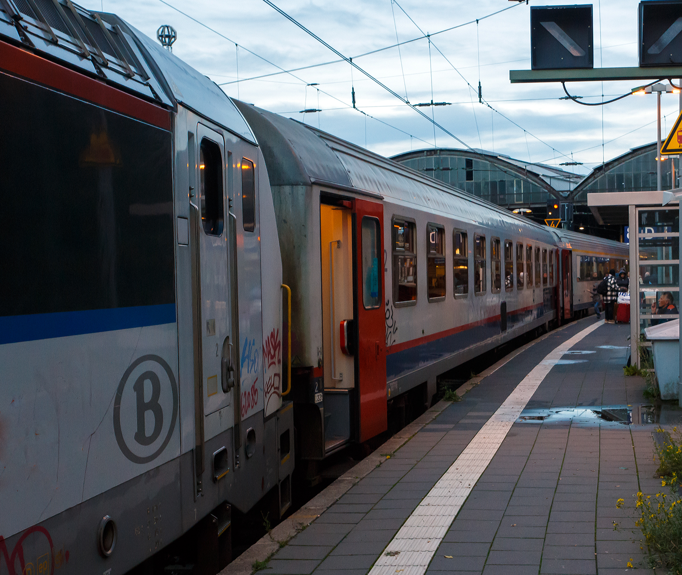 SNCB/NMBS - I10 Reisezugwagen (Schnellzugwagen für den internationalen Verkehr) der 2. Klasse, 51 88 21-70 010-2 B-B, ex B11 – 12710, eingereiht im Zugverband des euregioAIXpress (S41) von Liège-Saint-Lambert über Welkenraedt nach Aachen (d'Aix-la-Chapelle), am 21 Oktober 2025 im Hauptbahnhof Aachen. Der Wagen hat die RIC-Zulassungen für Frankreich, Deutschland, Österreich, die Niederlande, Italien, die Schweiz, Luxemburg, sowie natürlich Belgien (F, D, A, NL, I, CH, L, B).

Die Gattung I10 sind eine Serie von ursprünglich 95 Schnellzugwagen der Nationalen Gesellschaft der Belgischen Eisenbahnen (NMBS/SNCB), die in den Jahren 1987 und 1988 hergestellt wurden. Abgeleitet von den Eurofima-Wagen aus den 1970er Jahren entwickelte die NMBS/SNCB ab 1984 die neue I 10-Serie. Diese Wagen trugen viele Merkmale der Eurofima-Wagen, waren aber alle als Großraumwagen ausgeführt und besitzen einen einheitlichen Wagenkasten. Von den normalen Eurofima-Wagen unterscheiden sie sich vor allem durch die fehlende Schürze unter den seitlichen Längsträgern. Zwischen den Türen befinden sich jeweils elf 1.200 Millimeter breite Fenster plus die der WC´s auf einer Wagenseite. Davon wurden 15 Wagen als erster Klasse-Fahrzeuge und 45 Fahrzeuge mit der zweiten Wagenklasse ausgeführt. Da diese Wagen nicht klimatisiert sind, wurden die üblichen M4-Fenster mit Schiebeluke verwendet, wie sie für belgische Inlandswagen typisch sind. Die 35 Wagen der zweiten Klasse mit Klimaanlage B11 (HVAC) besitzen hingegen feststehende Fenster. Die 15 Erste-Klasse-Wagen des Typs A11t bieten 66 Sitzplätze, die 80 Zweite-Klasse-Wagen des Typs B11t haben 86 Sitzplätze.

Eingesetzt wurden die I 10-Wagen ursprünglich im internationalen Verkehr nach Italien, Deutschland und in die Schweiz. Nach der Einstellung der meisten internationalen Züge sind die Wagen heute nur noch im Interregio von Liers nach Luxemburg und in Verstärkerzügen zur Hauptverkehrszeit, oder wie hier im S41 dem euregioAIXpress nach Aachen zu finden.

TECHNISCHE DATEN:
Spurweite: 1.435 mm (Normalspur)
Anzahl der Achsen: 4 (2´2´)
Länge über Puffer: 26.400 mm
Wagenkastenlänge: 26.100mm
Drehzapfenabstand: 19.000 mm
Achsstand im Drehgestell: 2.560 mm
Drehgestelle: FIAT Y 0270 S t.34
Achsstand (gesamt): 21.560 mm
Wagenkastenbreite: 2825 mm
Höhe über SO: 4.050 mm
Eigengewicht: 41 t
Höchstgeschwindigkeit: 160 km/h
Sitzplätze: 86 in der 2. Klasse im Großraumabteil
Toiletten: 2 (geschlossenes System)
