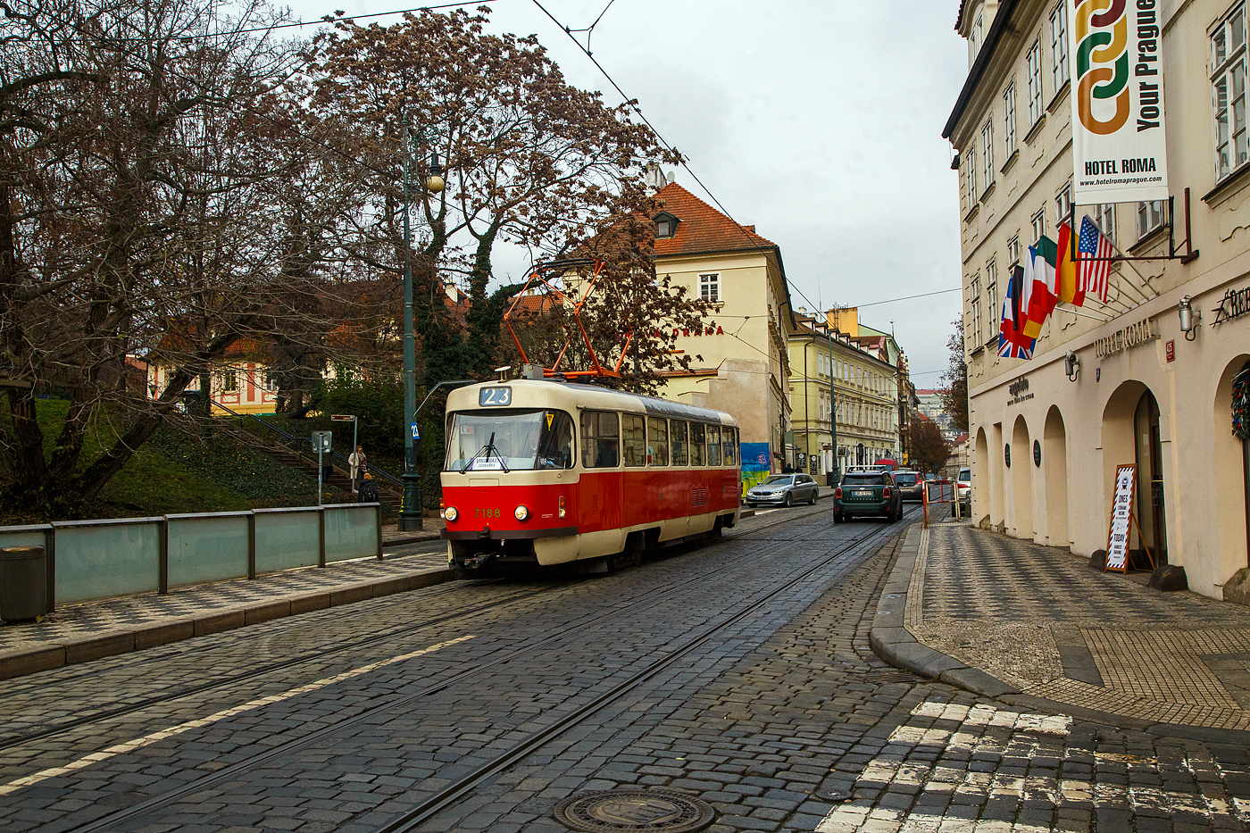 Straenbahn Prag, der Triebwagen DPP 7188 erreicht, als sog. nostalgische Linie 23 (Krlovka – Malostransk – Nrodn divadlo – Zvonařka) am 23.11.2022 die Station jezd (jezd / Praha). Links sieht man auch die Talstation jezd der Petřn-Standseilbahn.

Der Triebwagen ist ein ČKD Tatra T3 SUCS, er wurde 1986 von ČKD Tatra in Prag unter Fabriknummer 175 352 gebaut. 

ČKD Tatra T3 SUCS:
Da bereits ab Ende der 1970er Jahre in grerem Umfang etliche Wagen vom Typ T1 verschrottet wurden und auch der restliche Wagenpark von diesem Typ schon das Ende erreicht hatte, mussten dringend neue Fahrzeuge fr Prag her. Es war Anfang der 1980er Jahre geplant den neuen Gelenkwagentyp in greren Stckzahlen zu bestellen. Da dieser aber immer noch nicht zur Verfgung stand und zum anderen die Produktion der alten Wagen vom Typ T3 Ende 1976 auslief, fanden Verhandlungen mit dem CKD-Tatra Werken ber neue Fahrzeuge die kurzfristig lieferbar wren statt. Da die Technik der Thyristortechnik (TV1) schon veraltet war und nur mit teurem Aufwand zum Einbau gekommen wre, entschied man sich fr den Bau der Exportversion vom Typ T3SU. Dieser Wagentyp hatte aber wieder den herkmmlichen PCC-Beschleuniger als Steuerung. Besonderheiten gegenber dem bisherigen T3 war die Serienmig ausgestattete geschlossene Fahrerkabine, mehr Sitzpltze und der Dachaufstieg befindet sich nun an der hinteren Tr (beim T3 mittlere Tr). Da die Wagen vom Typ T3SU und T3SUCS die gleiche Vielfachsteuerung hatten wie die vom Typ T3 konnten sie auch mit dem Typ T3 in Traktion gefahren werden. Die ersten 20 Wagen (7001 - 7020) hatten eine 2+1 Bestuhlung im Fahrgastraum, weshalb sie auch Typenmig als T3SU bezeichnet wurden. Ab dem Wagen 7021 besaen alle weiteren Wagen die typische 1+1 Bestuhlung und wurden als T3SUCS bezeichnet.
