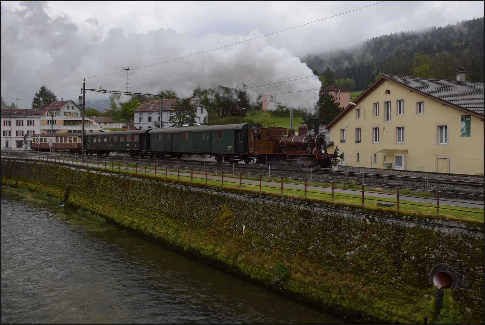 Vapeur Val-de-Travers: Train  Au fil de l'Areuse .

E 3/3 8511 in Couvet mit Areuse. Mai 2023.