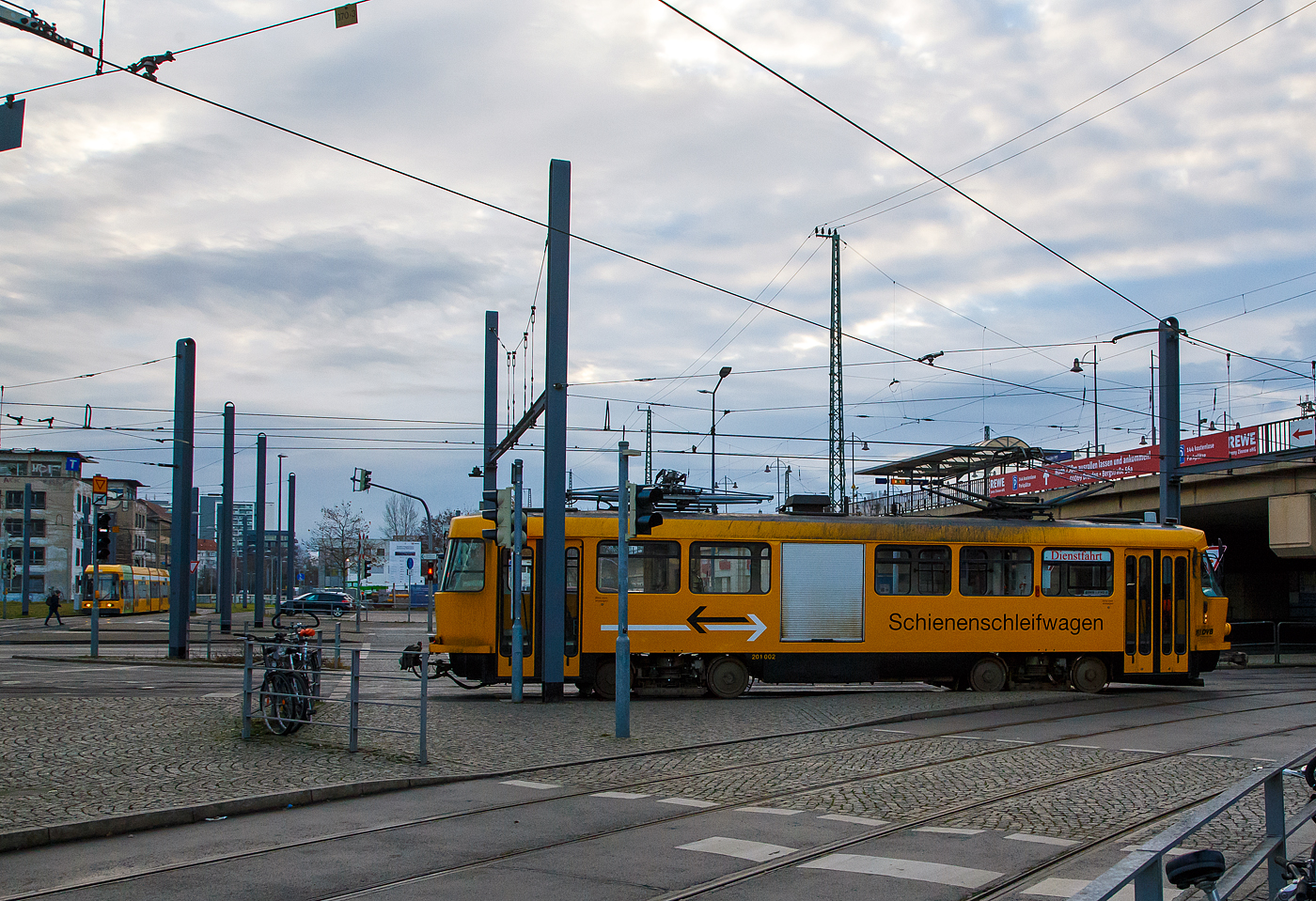 Zuvor konnte ich ihn in der anderen Fahrtrichtung und Seite sehen, hier stören nur etwas die Masten....
DVB 201 002-2 der Schienschleifwagen & Fahrleitungsenteisungswagen fährt auf Dienstfahrt am 08.12.2022 beim Hbf Dresden in Richtung Plauen (Süden). In Plauen ist eine Wendeschleife, dieser Arbeitstriebwagen ist ein Einrichtungsfahrzeug mit nur einem Führerstand.

Der Schienschleifwagen ist ein Tatra-Wagen vom Typ T4D und wurde 1975 von ČKD Tatra n.p in Prag unter der Fabriknummer 164-163 und als TW 222 504 an die DVB Dresdner Verkehrsbetriebe geliefert. 1982 erfolgte der Umbau zum Arbeitswagen als Schienschleifwagen und Umzeichnung in ATW729 062, 1984 wurde er in DVB 201 002-2 umgezeichnet. Im Dezember 2004 erhielt er einen mit zweitem Stromabnehmer zur Enteisung der Fahrleitung, man sieht hier auch deutlich den unterschied der beiden Stromabnehmer. Im Jahr 2009 wurde auf der rechten Seite ein Rolltor eingebaut.
