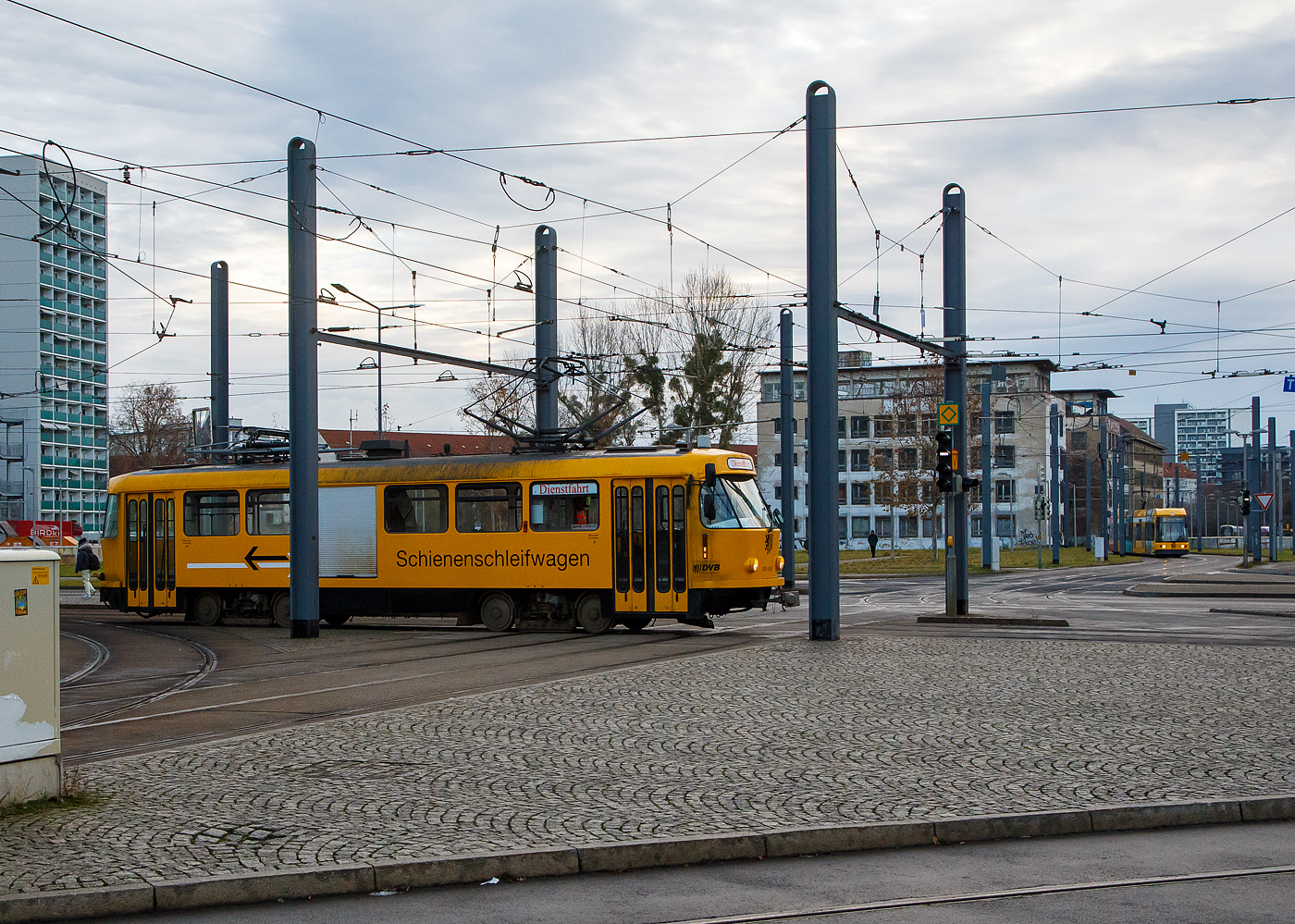 Zuvor konnte ich ihn in der anderen Fahrtrichtung und Seite sehen, hier stören nur etwas die Masten....
DVB 201 002-2 der Schienschleifwagen & Fahrleitungsenteisungswagen fährt auf Dienstfahrt am 08.12.2022 beim Hbf Dresden in Richtung Plauen (Süden). In Plauen ist eine Wendeschleife, dieser Arbeitstriebwagen ist ein Einrichtungsfahrzeug mit nur einem Führerstand.

Der Schienschleifwagen ist ein Tatra-Wagen vom Typ T4D und wurde 1975 von ČKD Tatra n.p in Prag unter der Fabriknummer 164-163 und als TW 222 504 an die DVB Dresdner Verkehrsbetriebe geliefert. 1982 erfolgte der Umbau zum Arbeitswagen als Schienschleifwagen und Umzeichnung in ATW729 062, 1984 wurde er in DVB 201 002-2 umgezeichnet. Im Dezember 2004 erhielt er einen mit zweitem Stromabnehmer zur Enteisung der Fahrleitung, man sieht hier auch deutlich den unterschied der beiden Stromabnehmer. Im Jahr 2009 wurde auf der rechten Seite ein Rolltor eingebaut.
